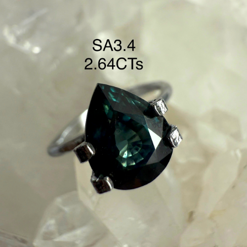 Silver ring with a large green gemstone on a textured white background