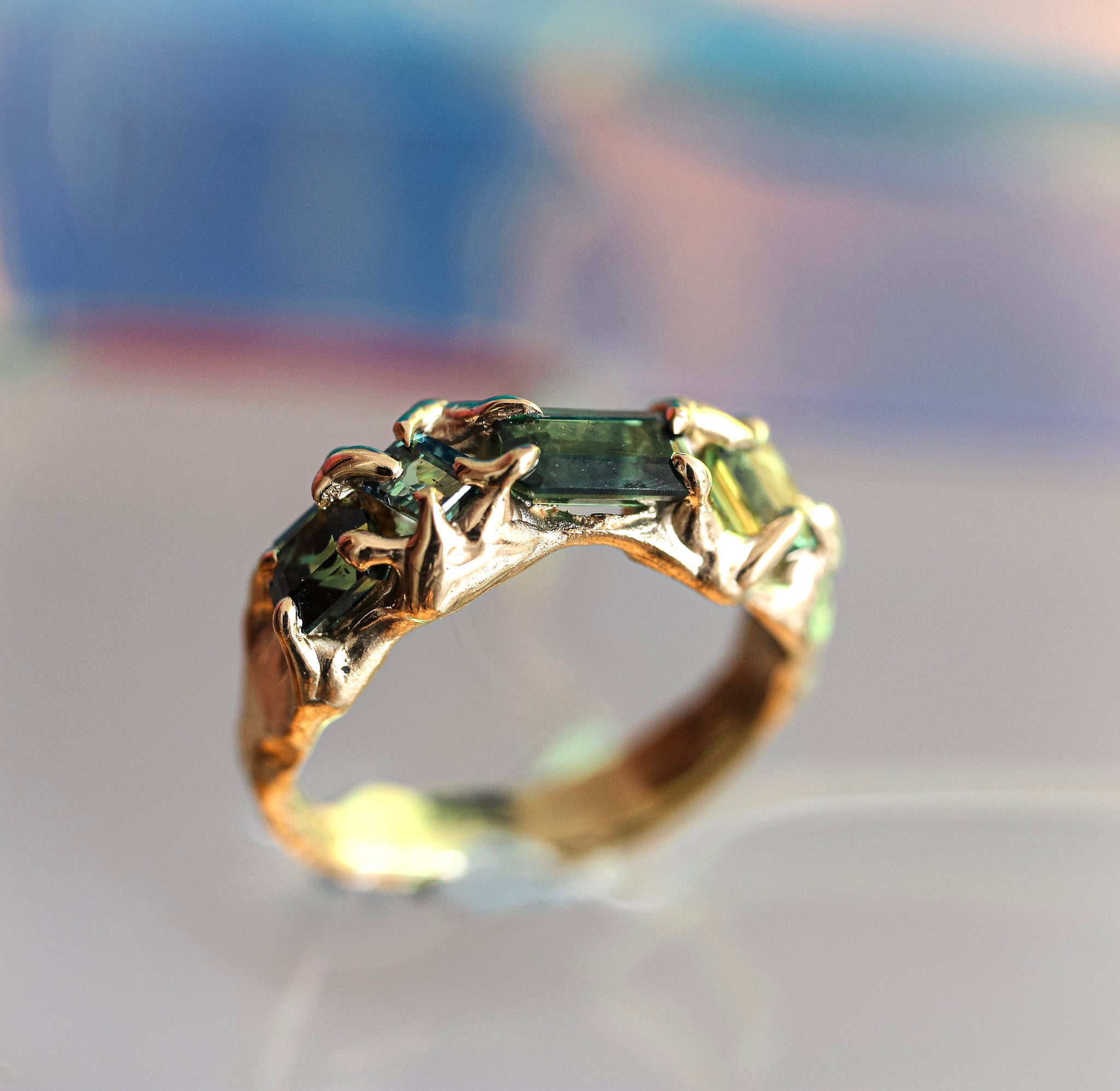 Gold ring with green australian sapphire on a blurred background