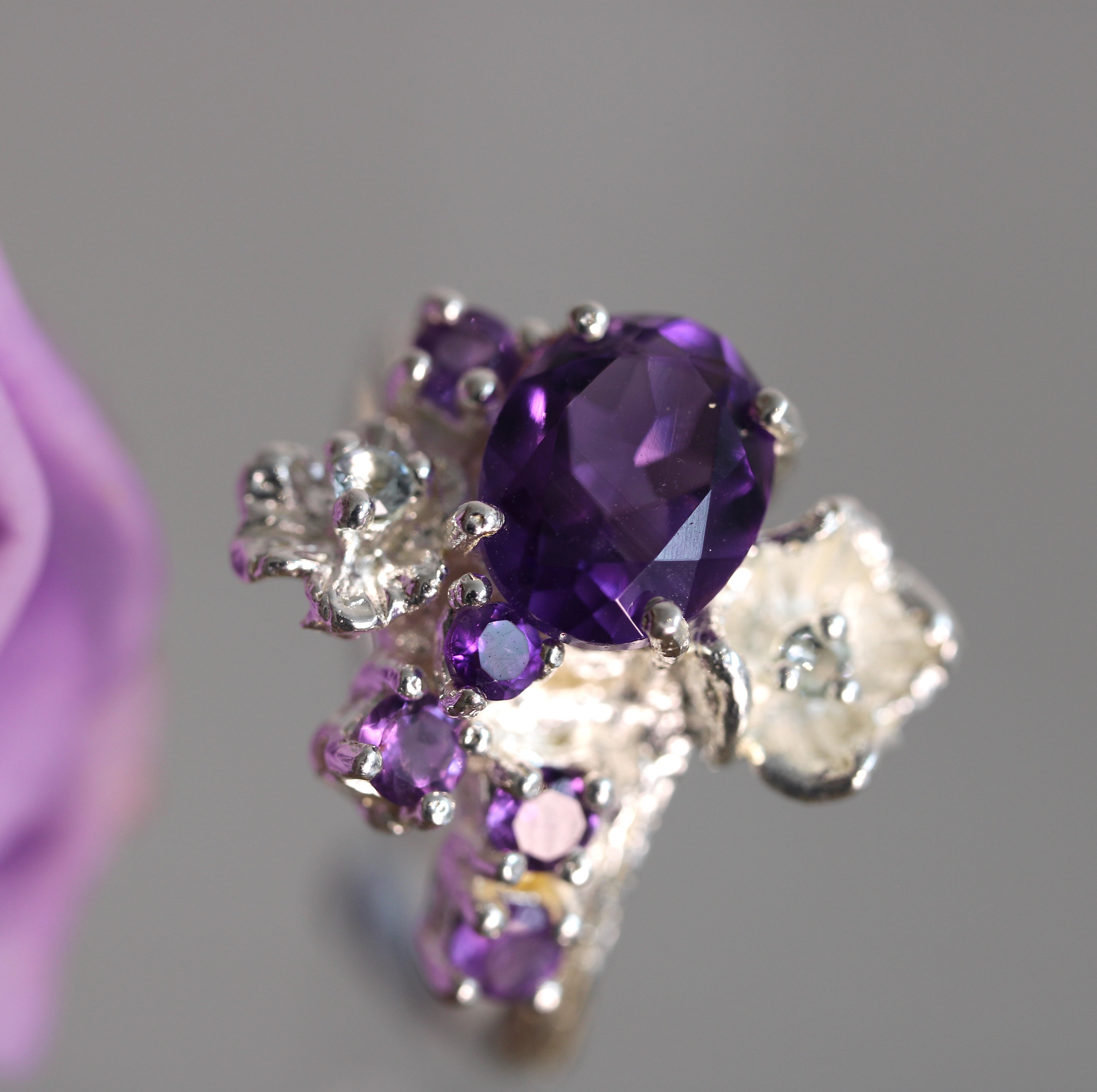 Silver ring with purple gemstone on a gray background