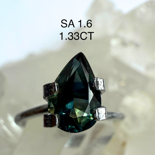 Teardrop-shaped gemstone ring with size and carat weight information on a textured white background