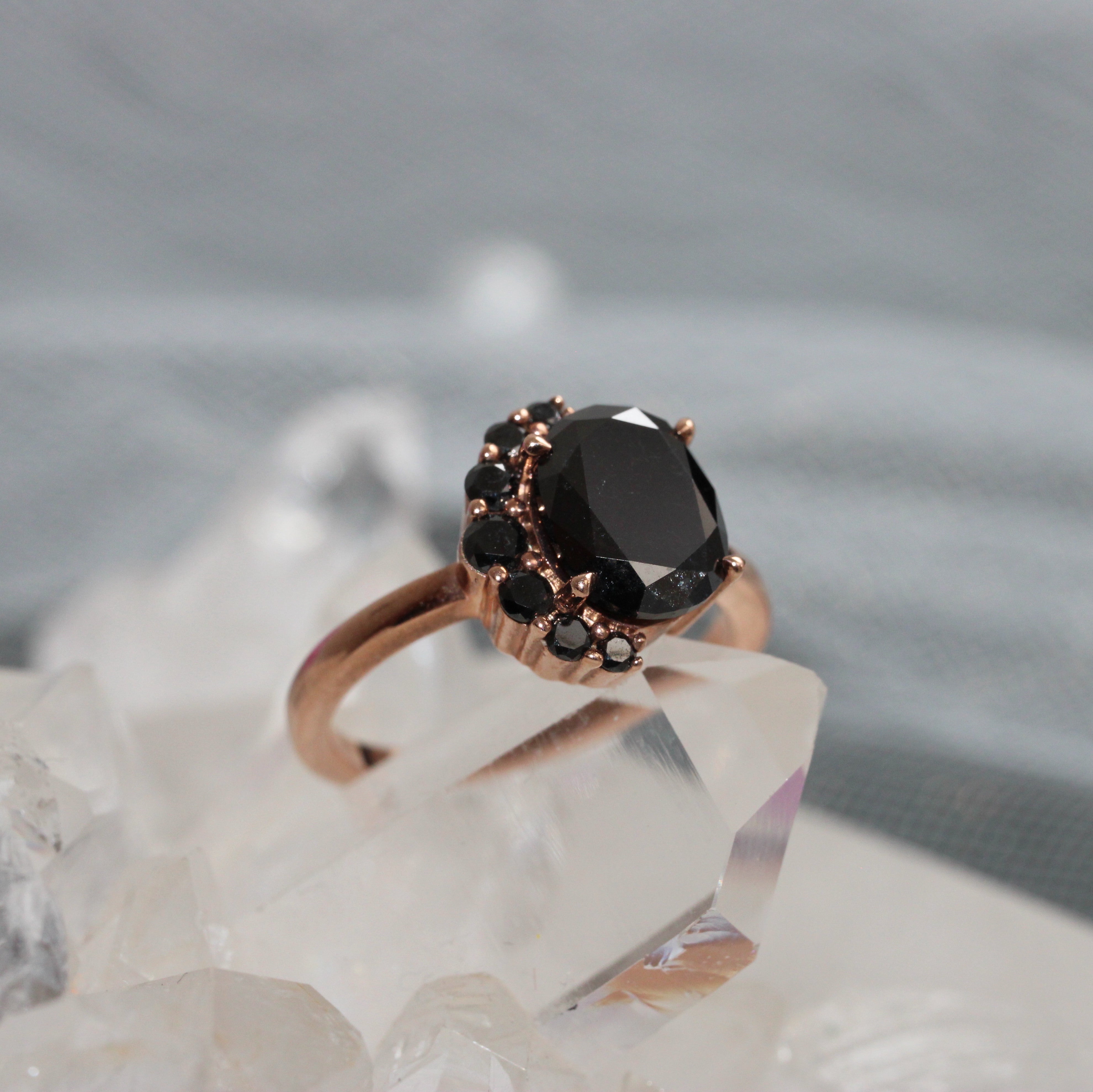 Rose gold ring with a black diamonds on a crystal background