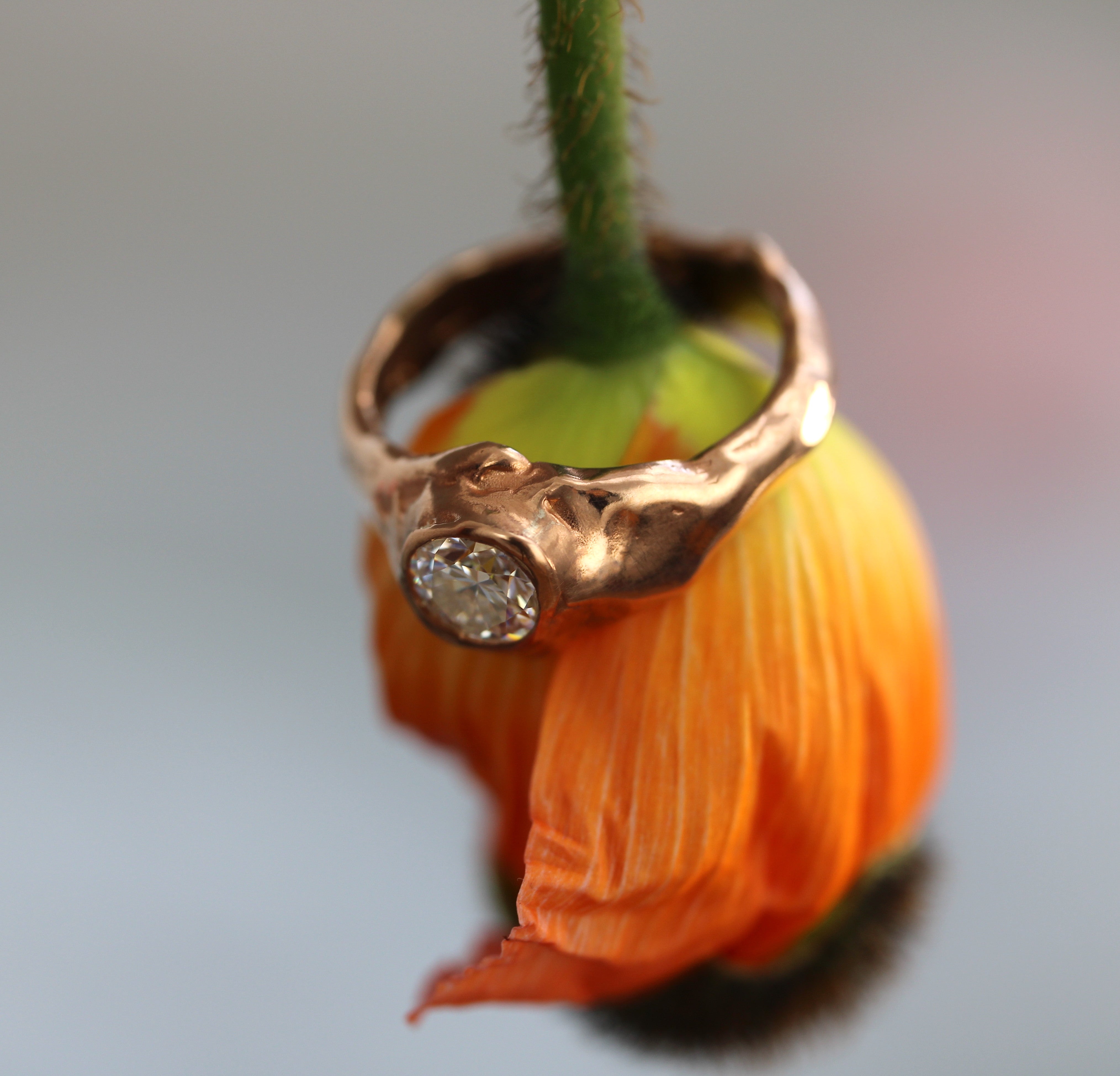 Rose gold ring with a diamond on an orange flower petal