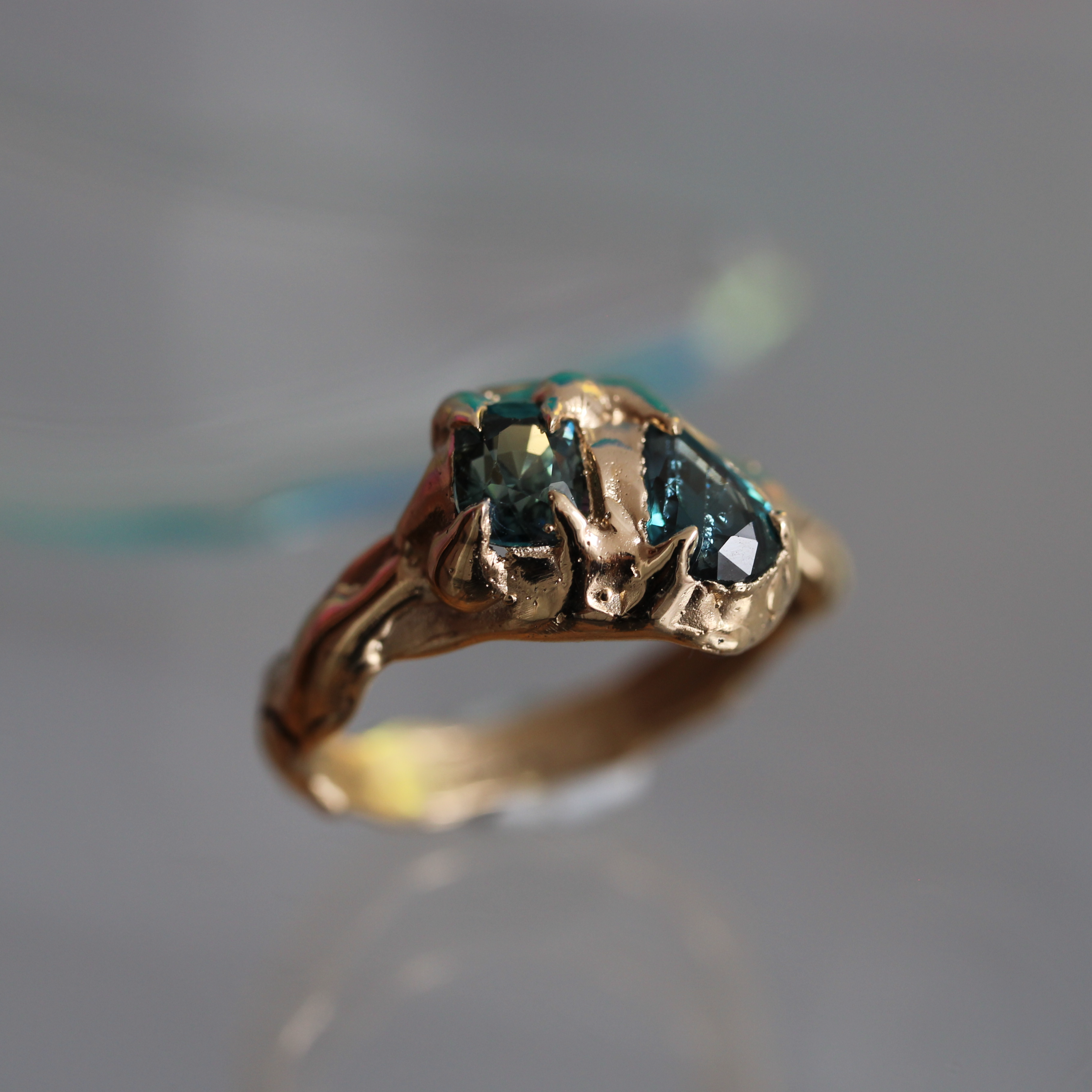 Gold ring with a green partii sapphire
gemstone on a reflective surface