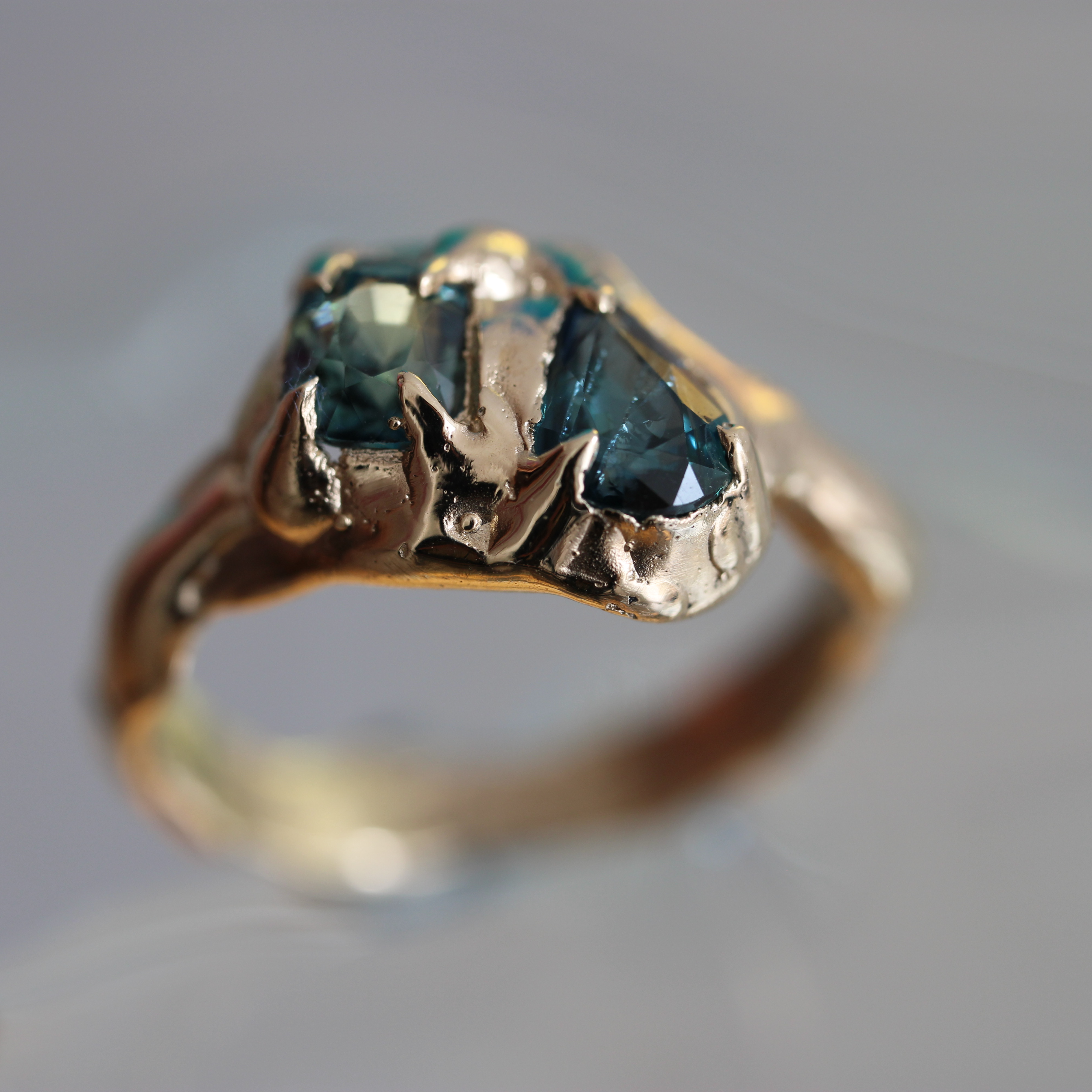 Gold ring with a green sapphir gemstone on a gray background