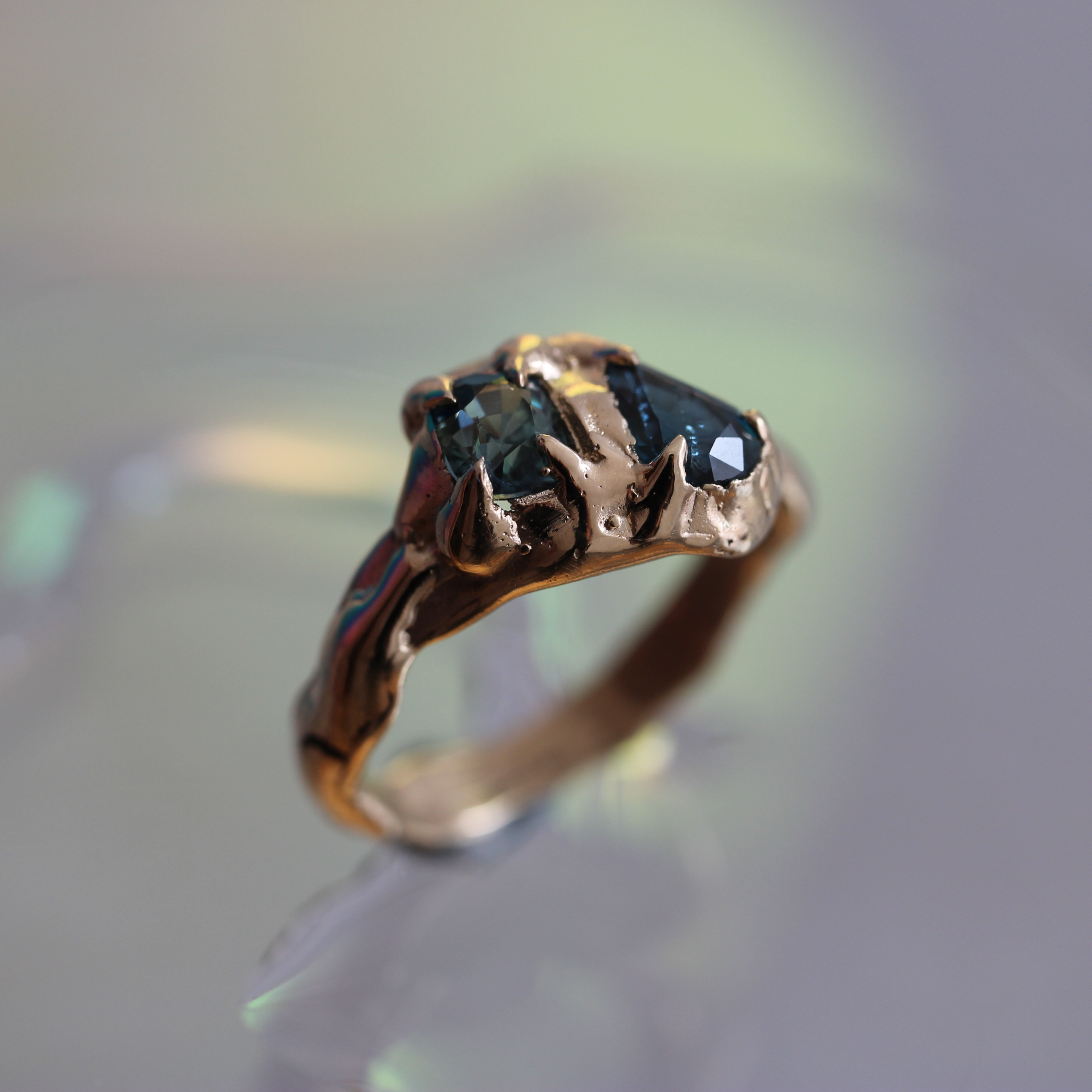 Gold ring with a central sapphire gemstone on a blurred background