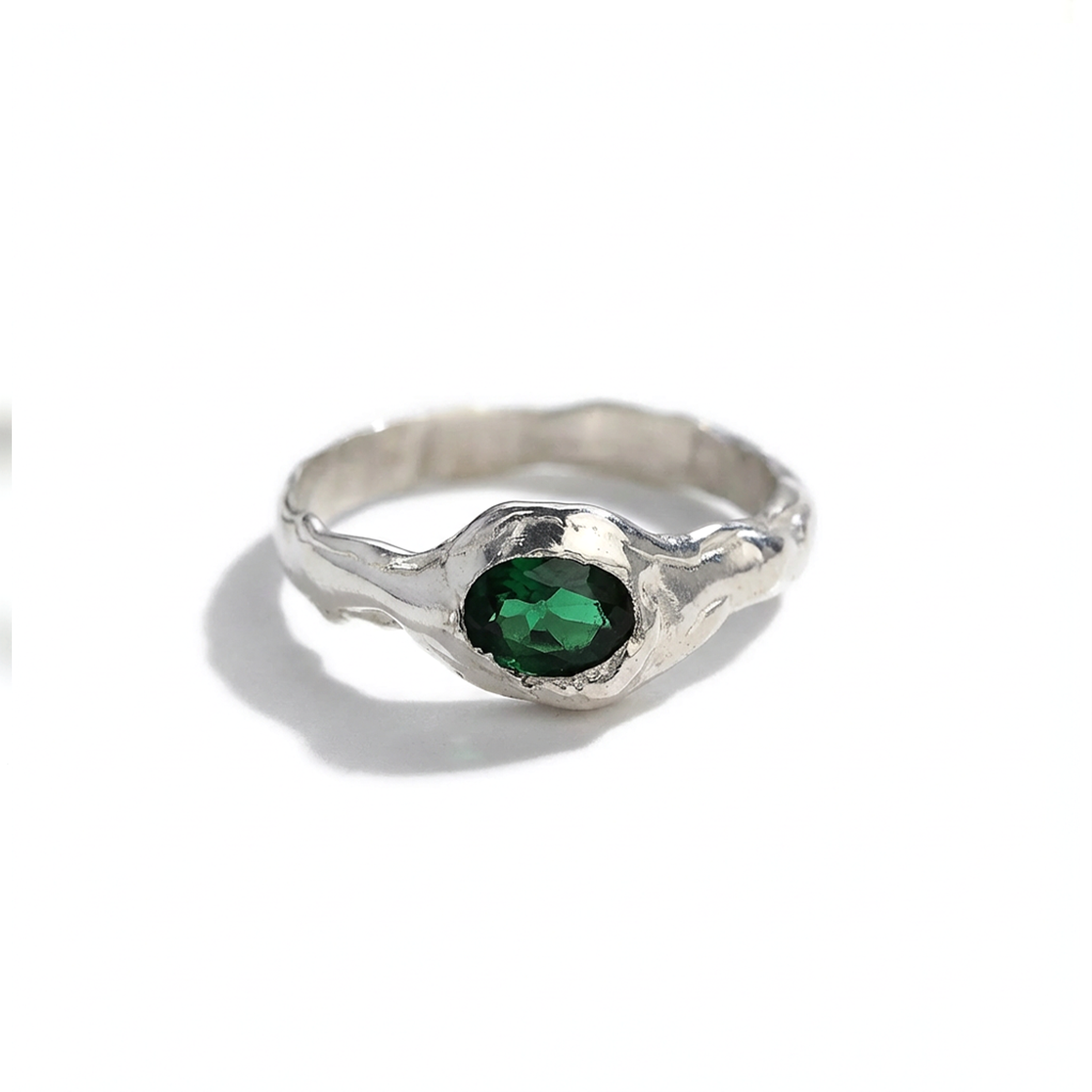 Silver ring with a green gemstone on a white background