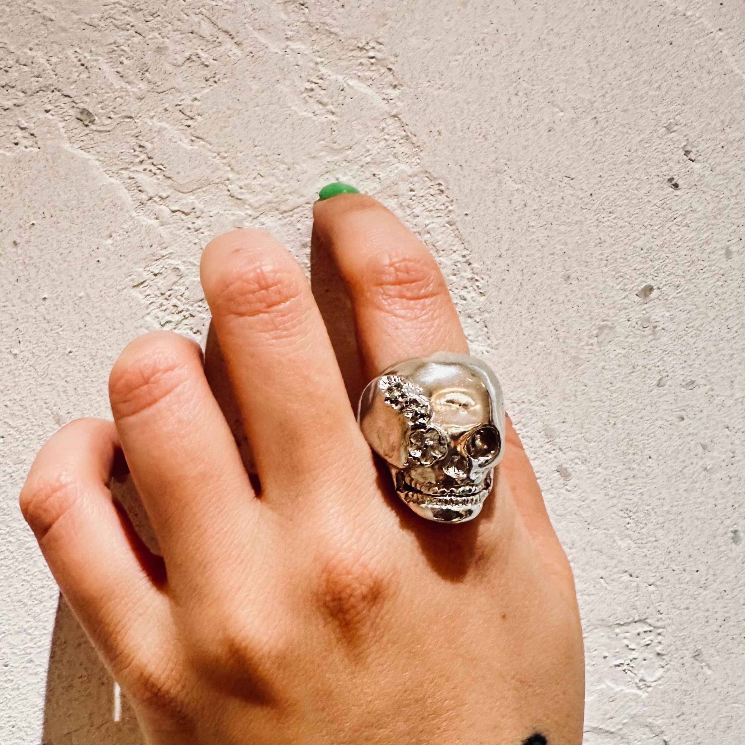 Silver skull ring with floral details on a white background