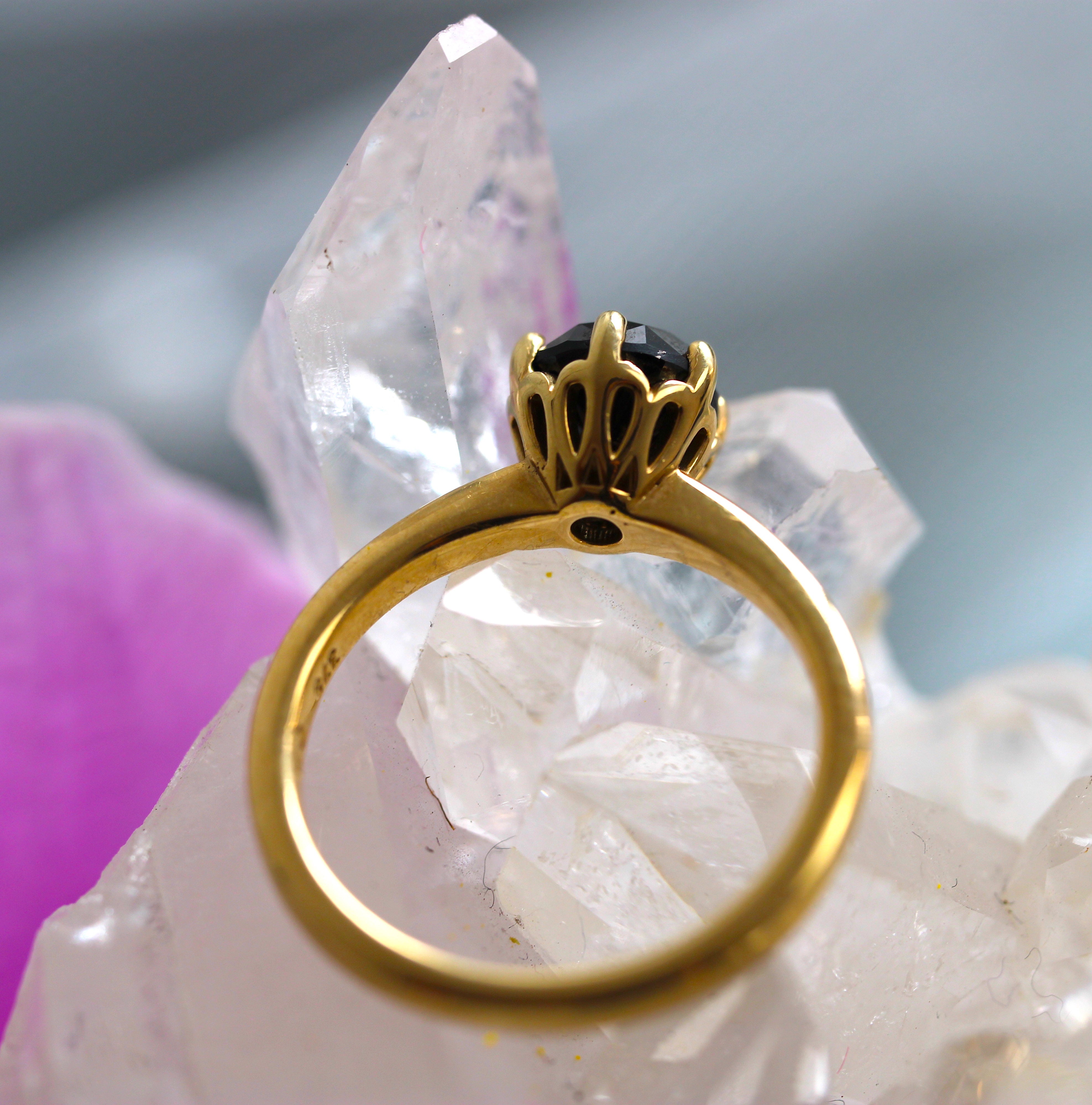 Gold ring with a black gemstone on a crystal background