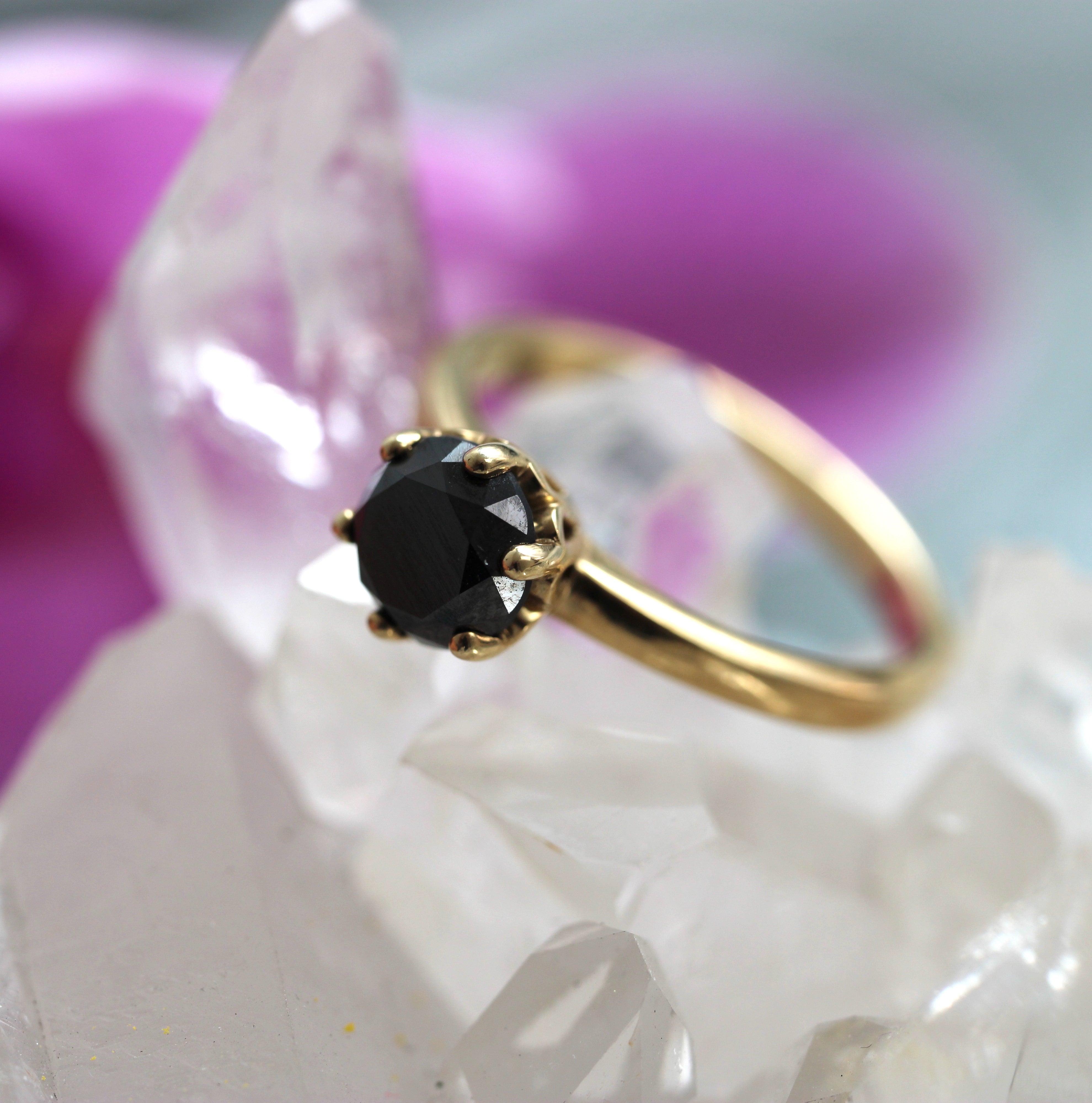 Gold ring with a black gemstone on a white and pink floral background