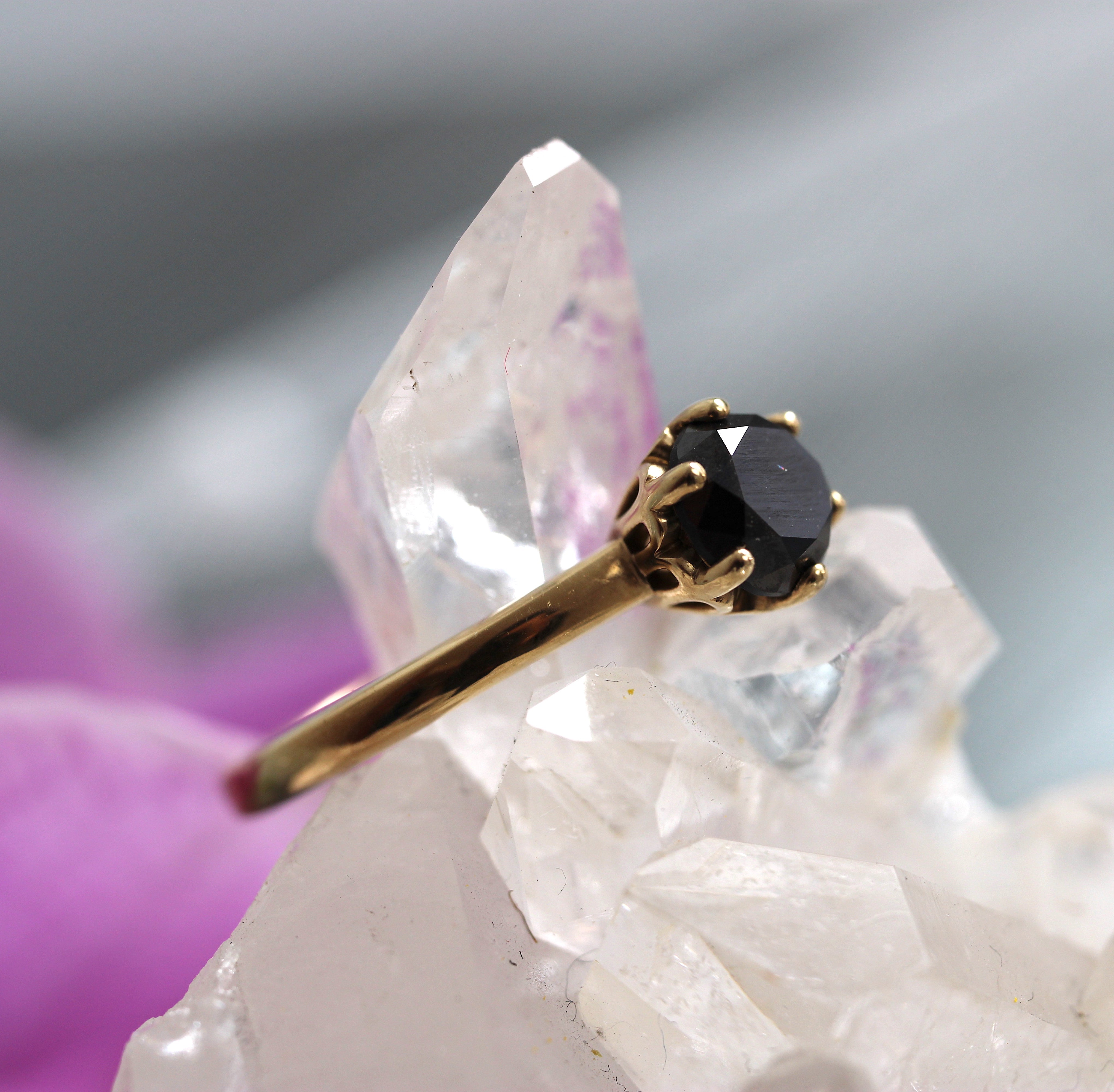 Gold ring with a black gemstone on a crystal background