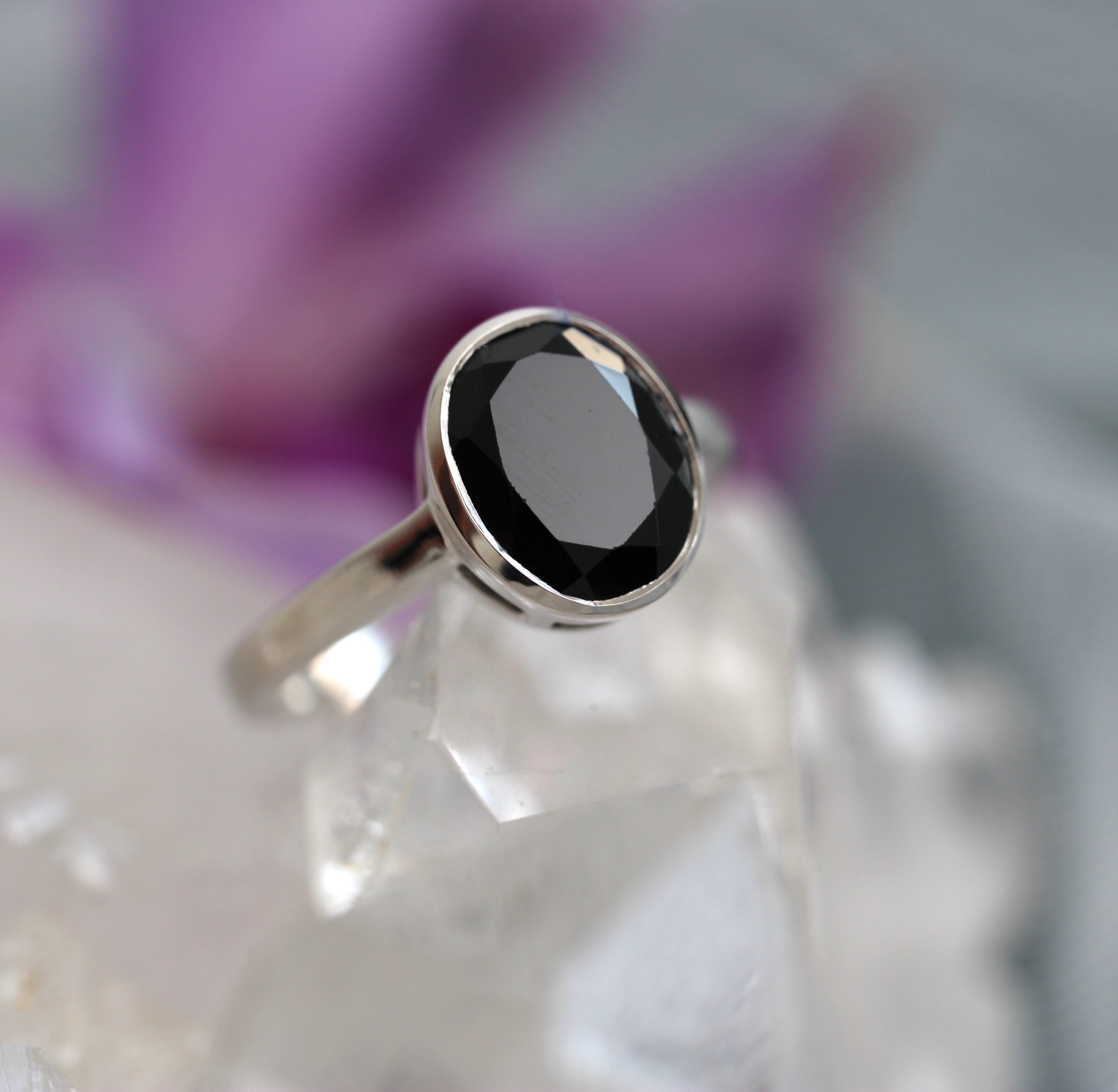 Silver ring with a black tourmaline gemstone on a crystal background