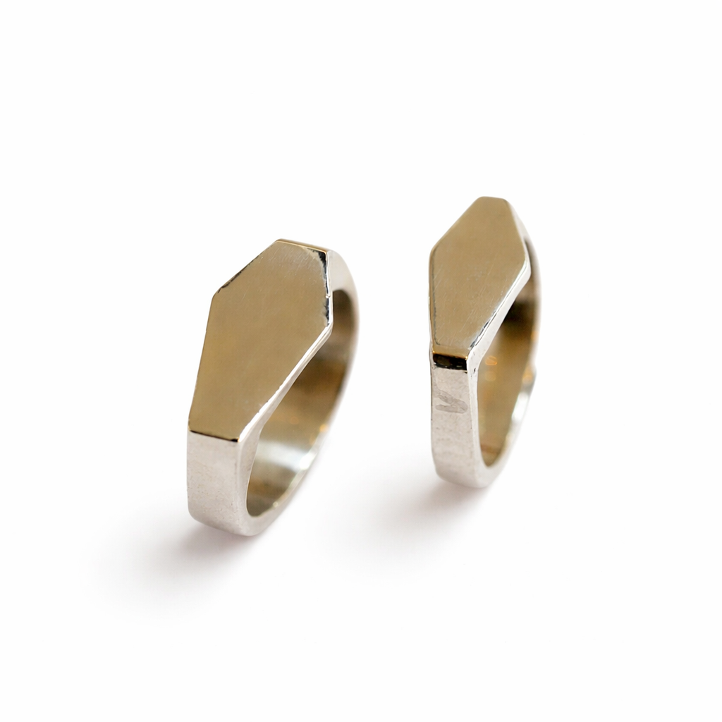 Pair of gold and silver geometric shaped signet rings on a white background