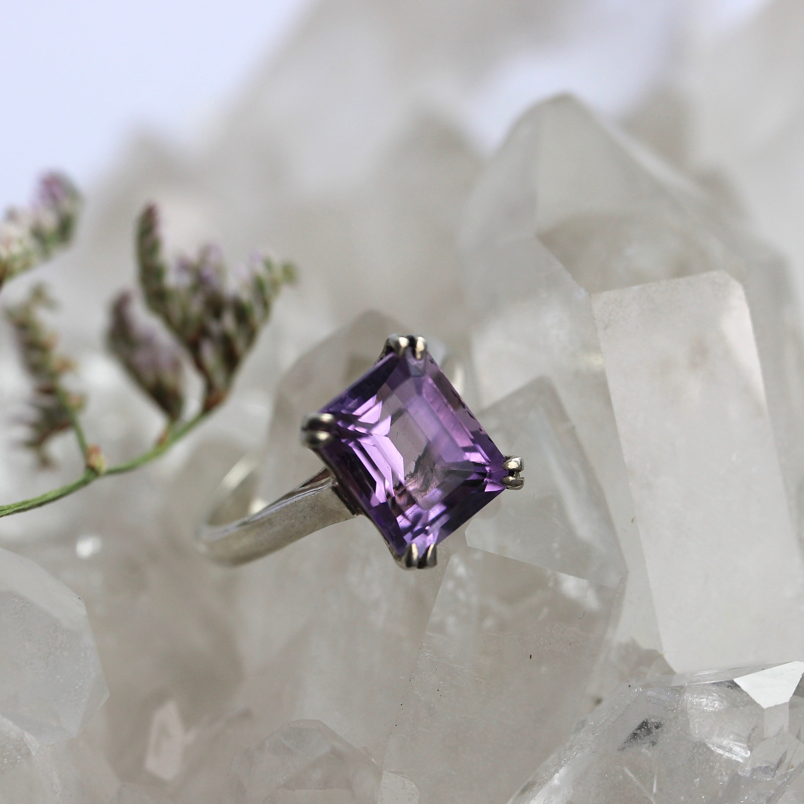 Amethyst ring on a crystal background with blurred flowers