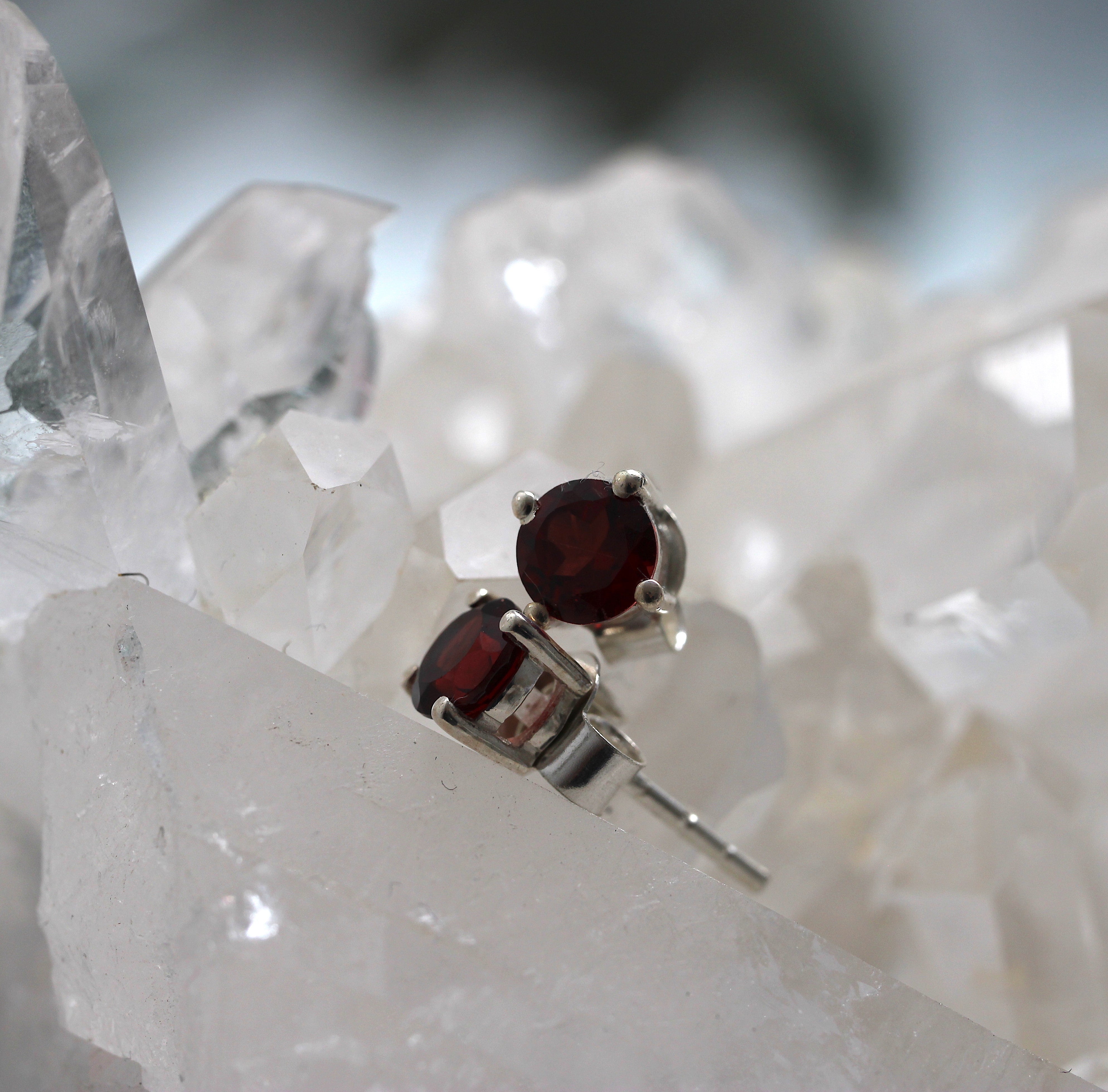 Silver earrings with red gemstones on a crystal background