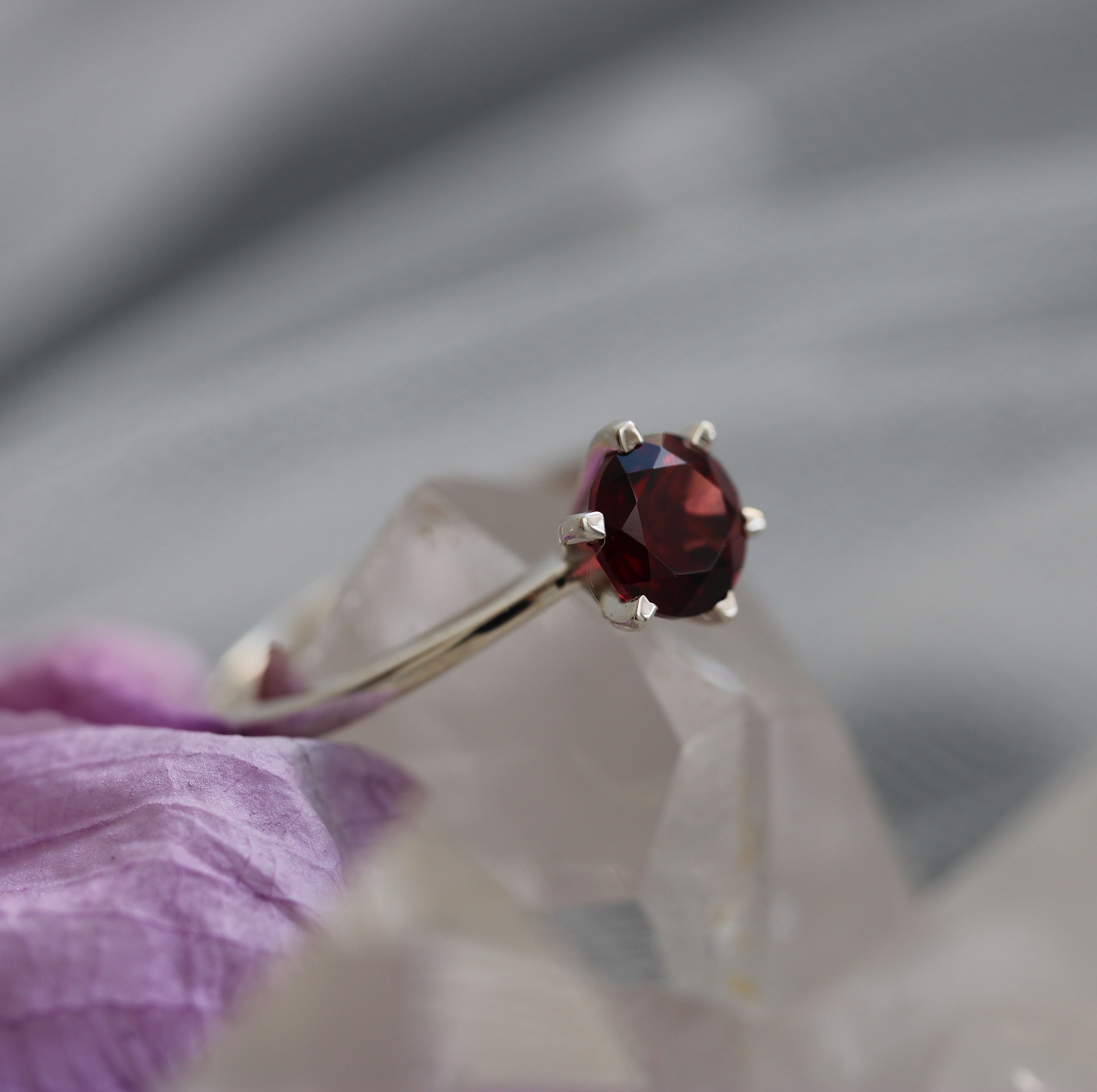 Ring with a red garnet gemstone on a gray background