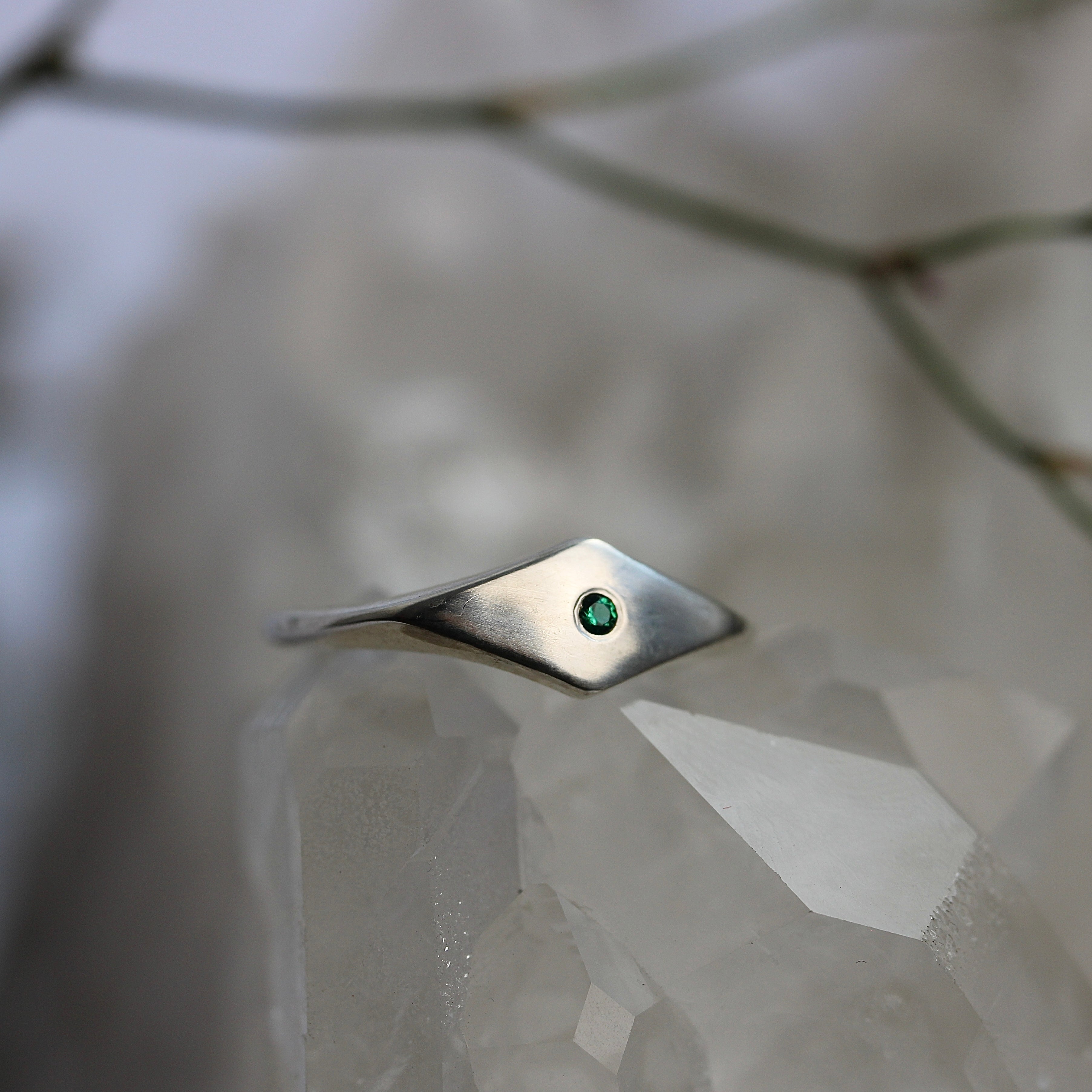 Silver ring with a green gemstone on a textured surface