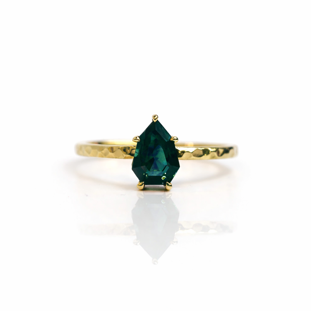 Gold ring with a green gemstone on a white background