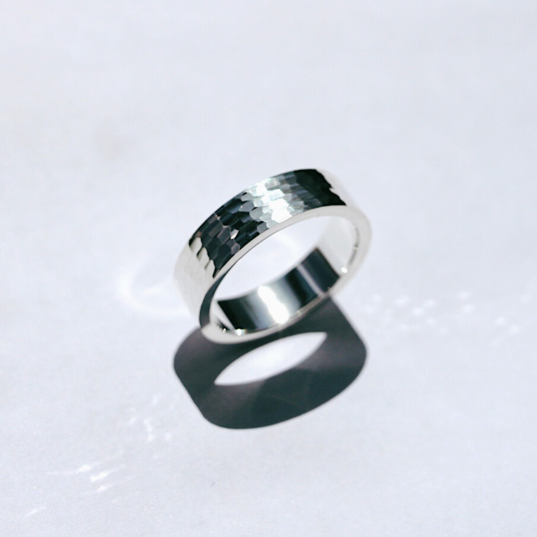 A hammered wedding band in silver, displayed on a white background.
