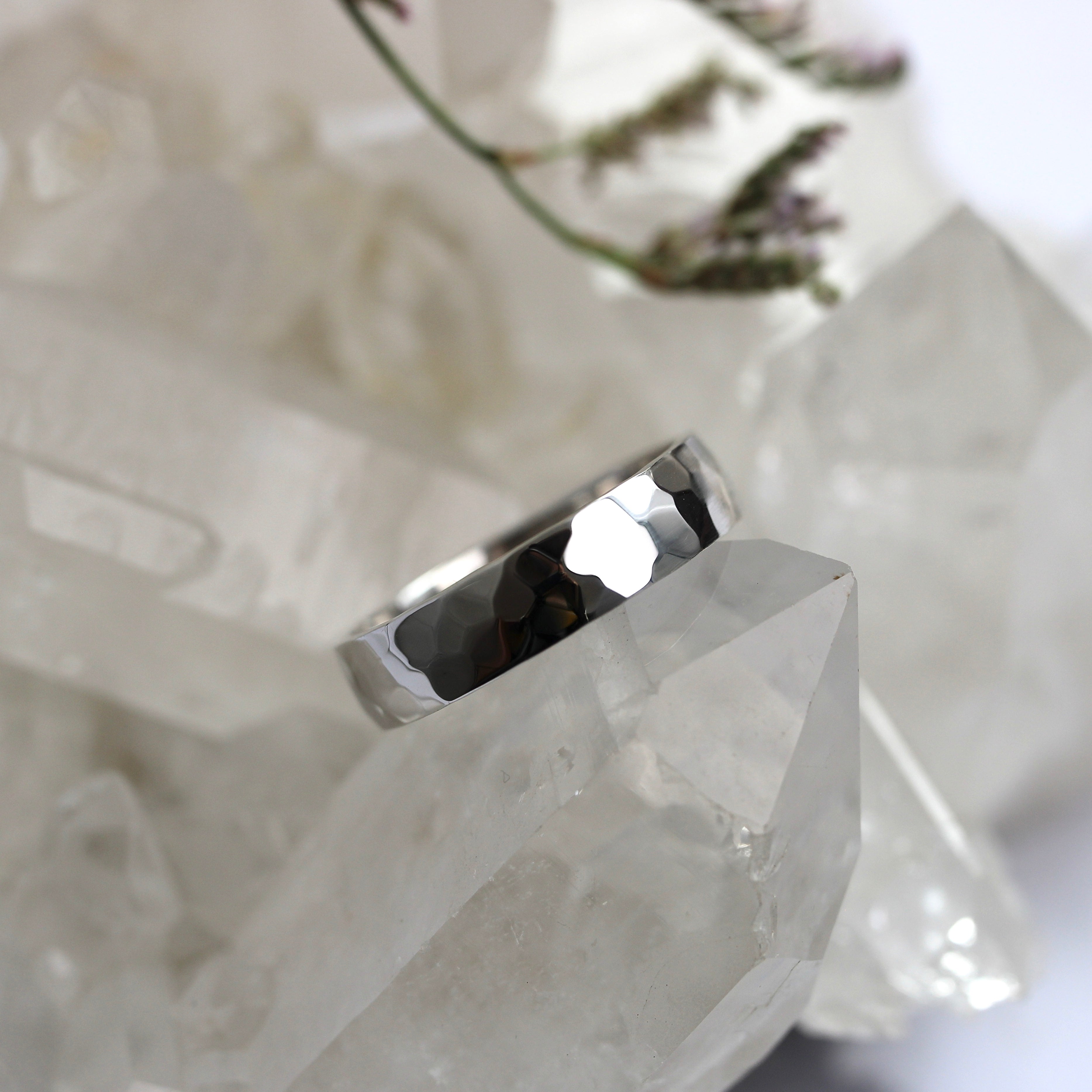 Silver ring on a crystal with a blurred floral background