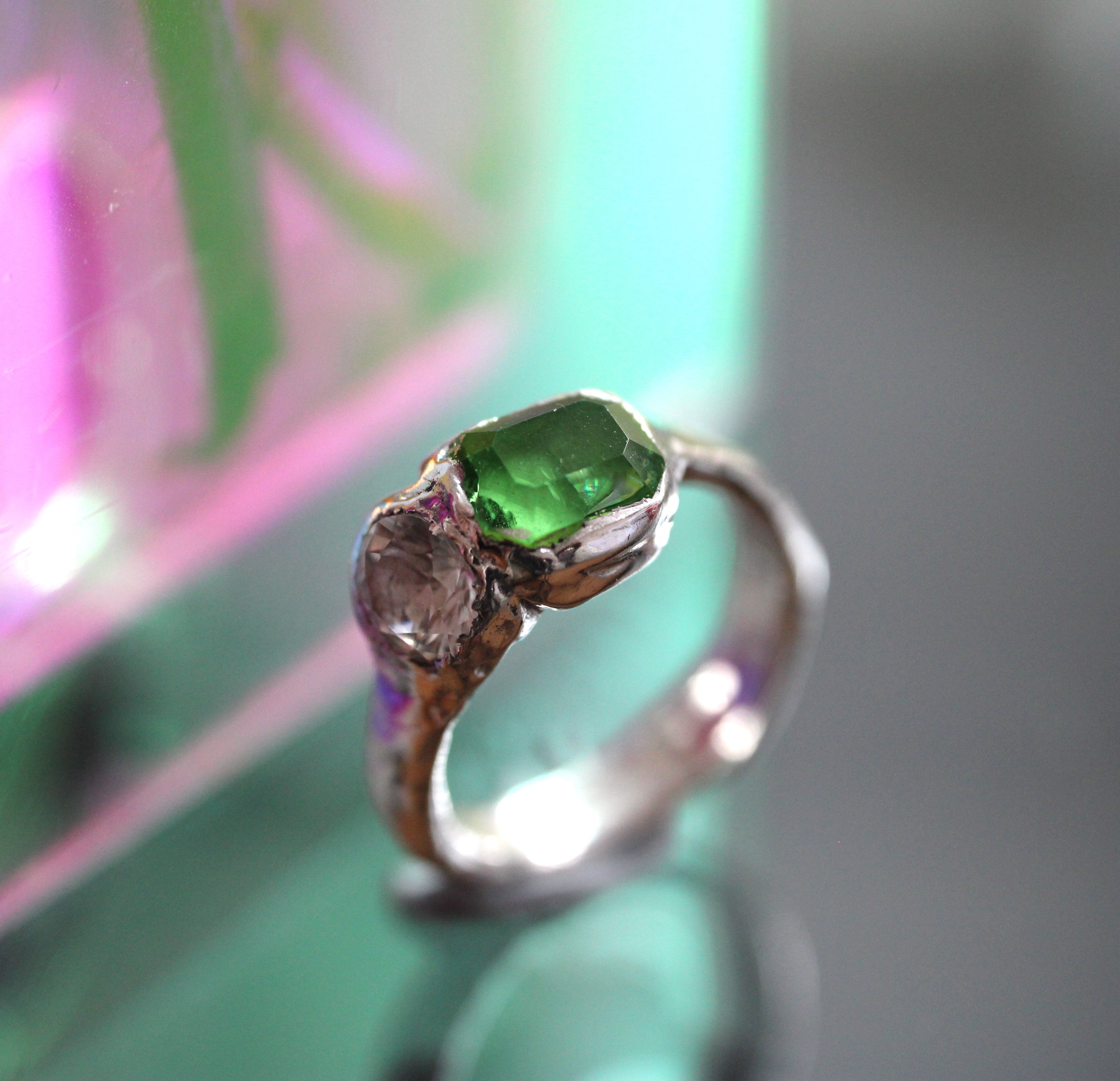 Silver ring with a green gemstone on a reflective surface