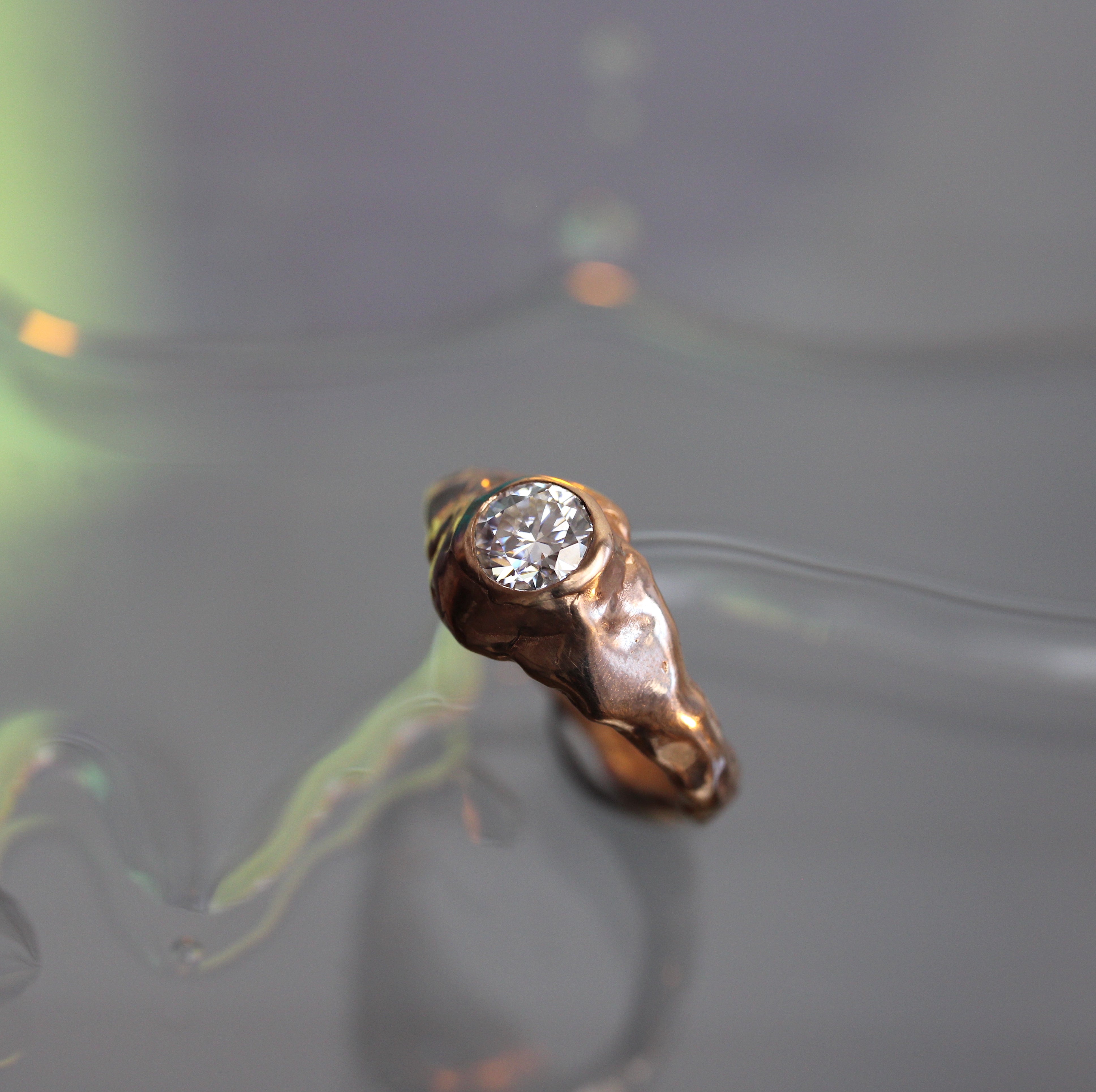 Gold ring with a diamond on a reflective surface