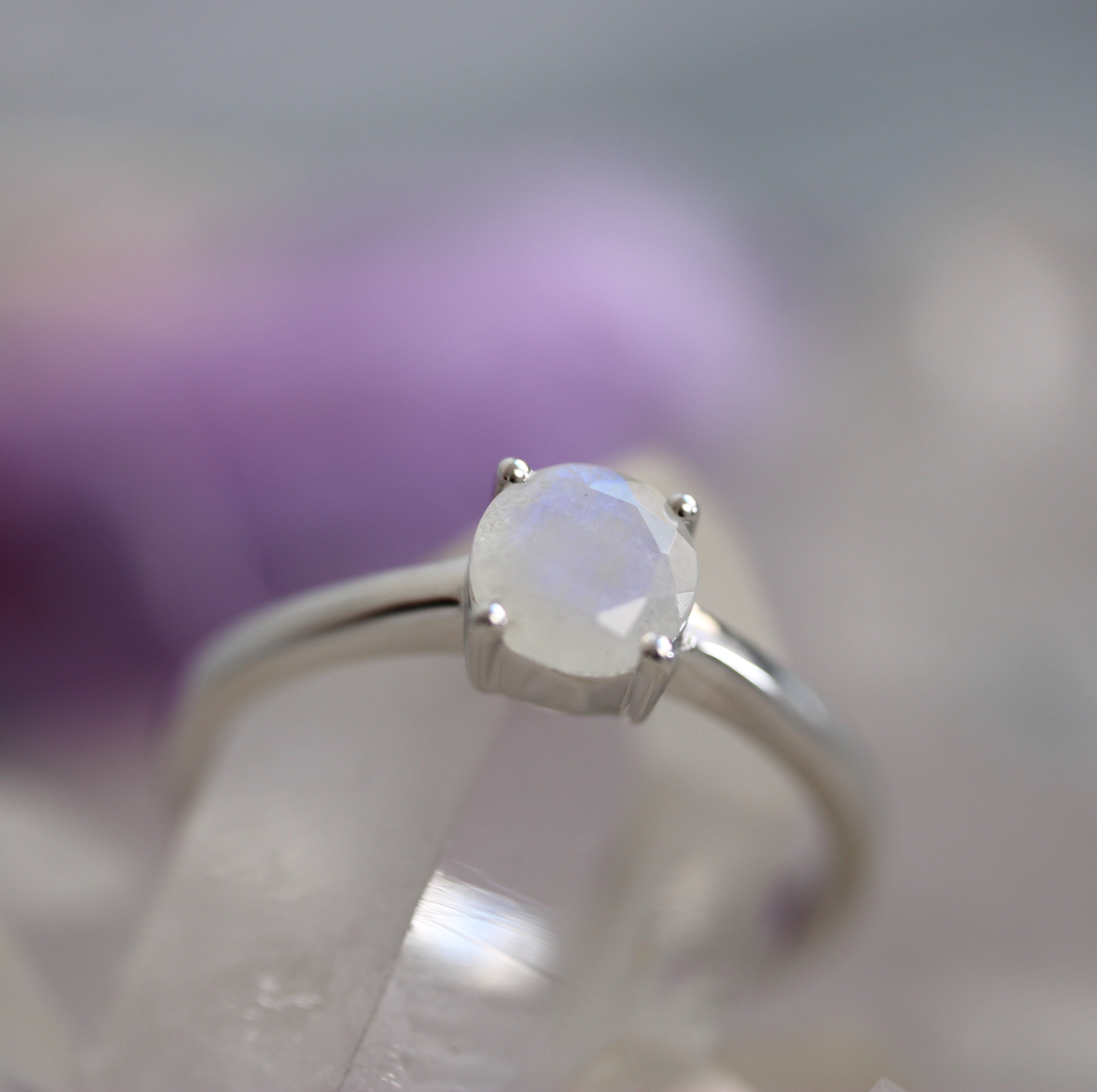 Silver ring with a round rainbow moonstone gemstone on a blurred background