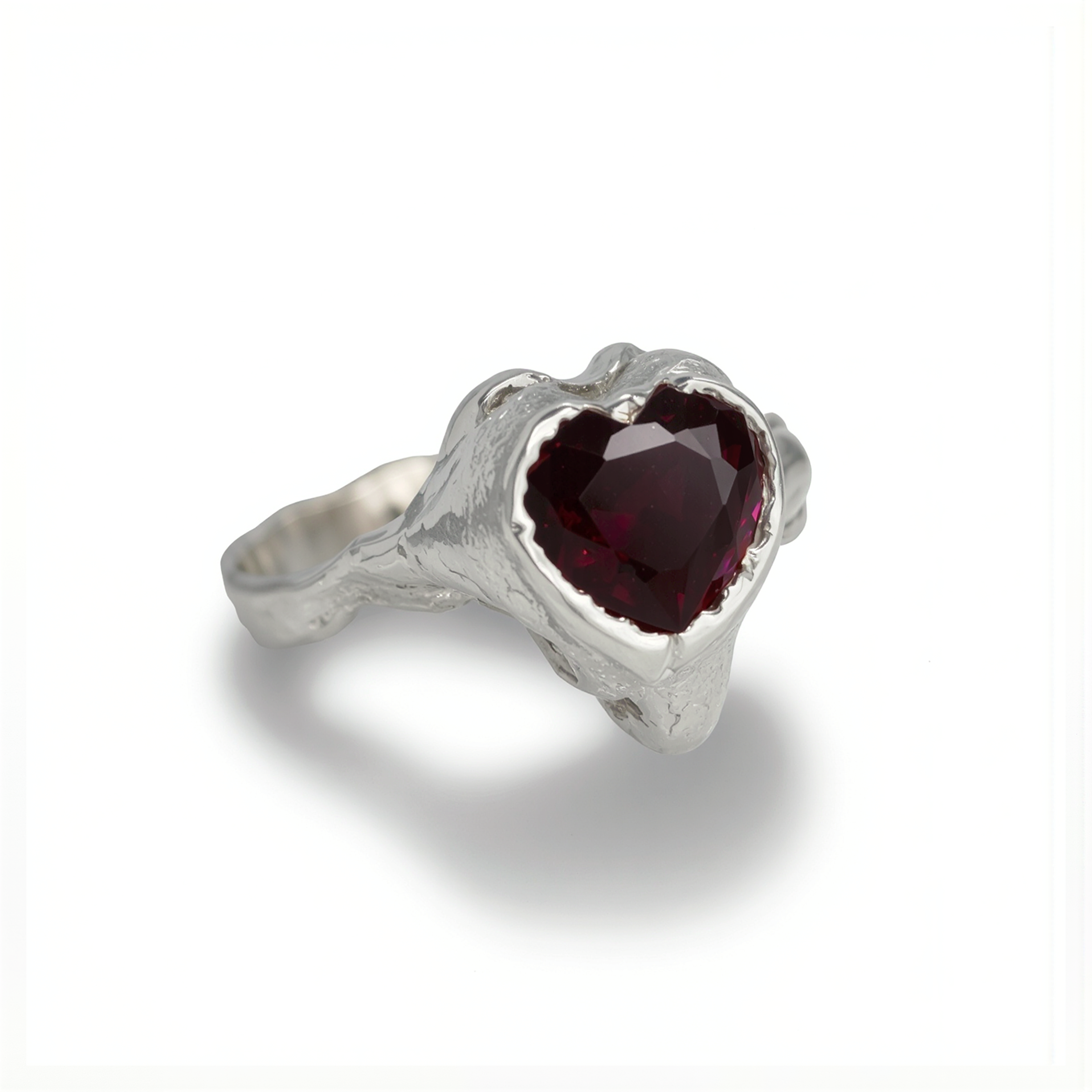 Silver ring with a heart-shaped red gemstone on a white background