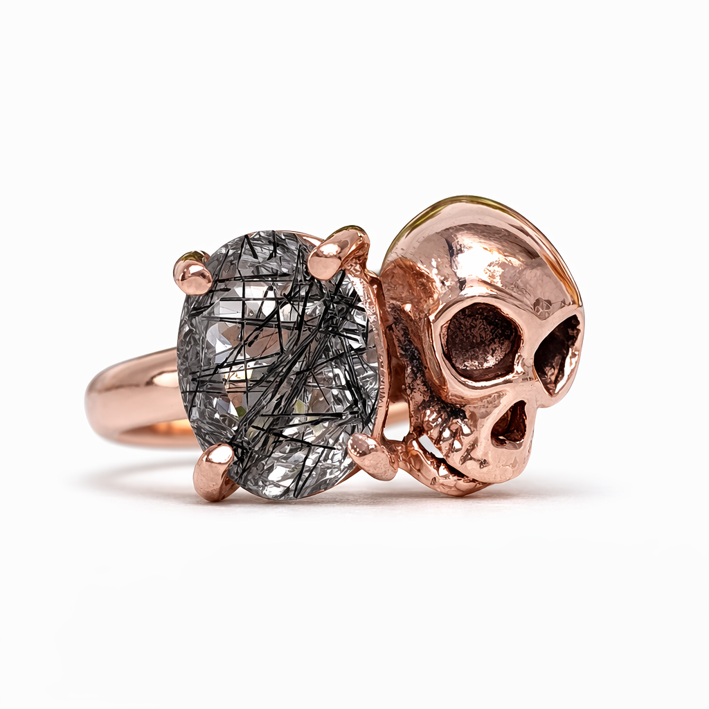 Rose gold skull ring with a large gemstone on a white background