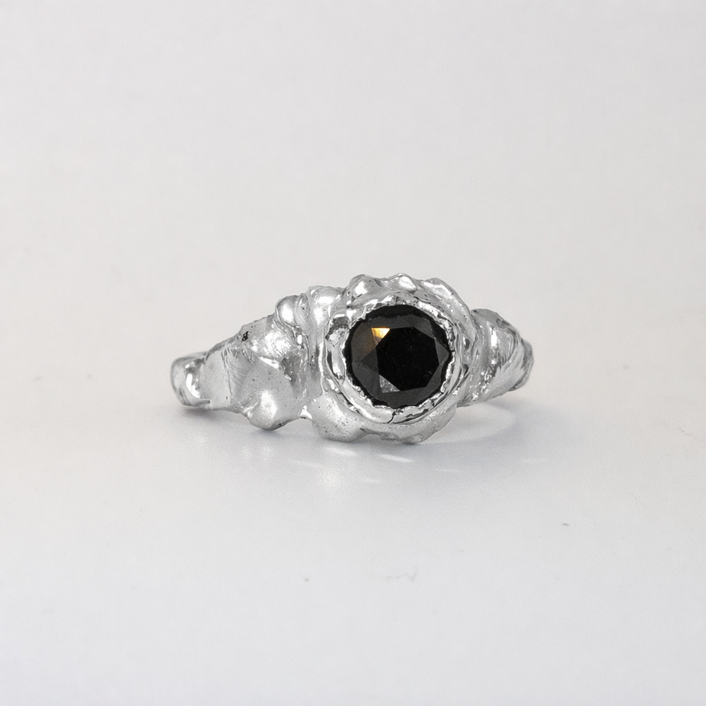 Silver ring with a black gemstone on a light gray background
