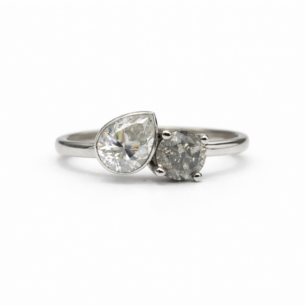 Silver ring with two pear-shaped diamonds on a white background