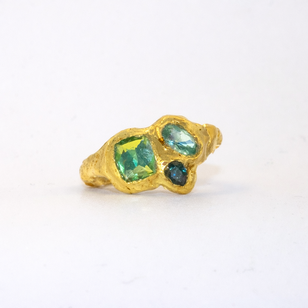 Gold ring with green sapphireson a white background