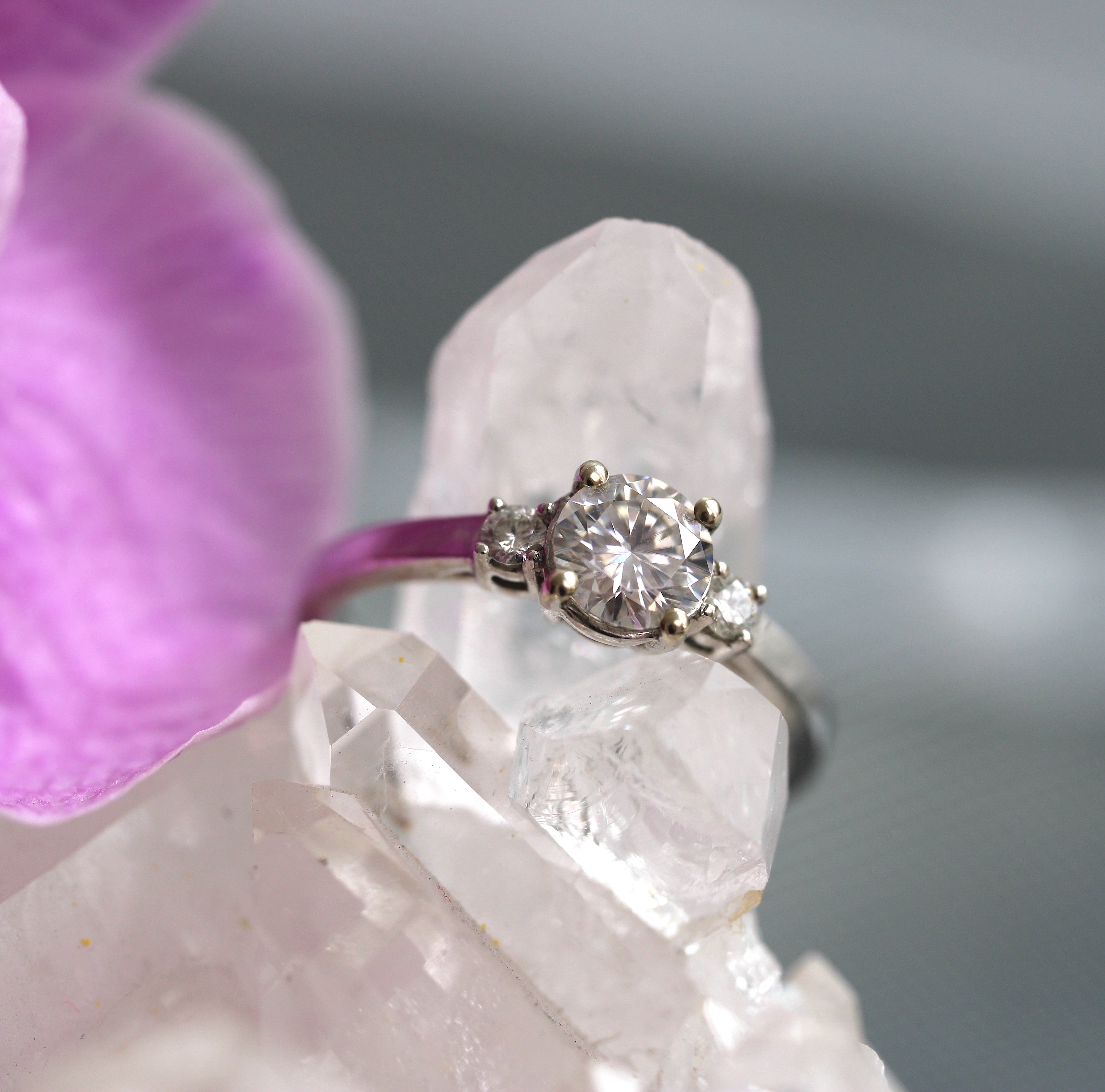 Diamond ring on a crystal with a pink orchid in the background