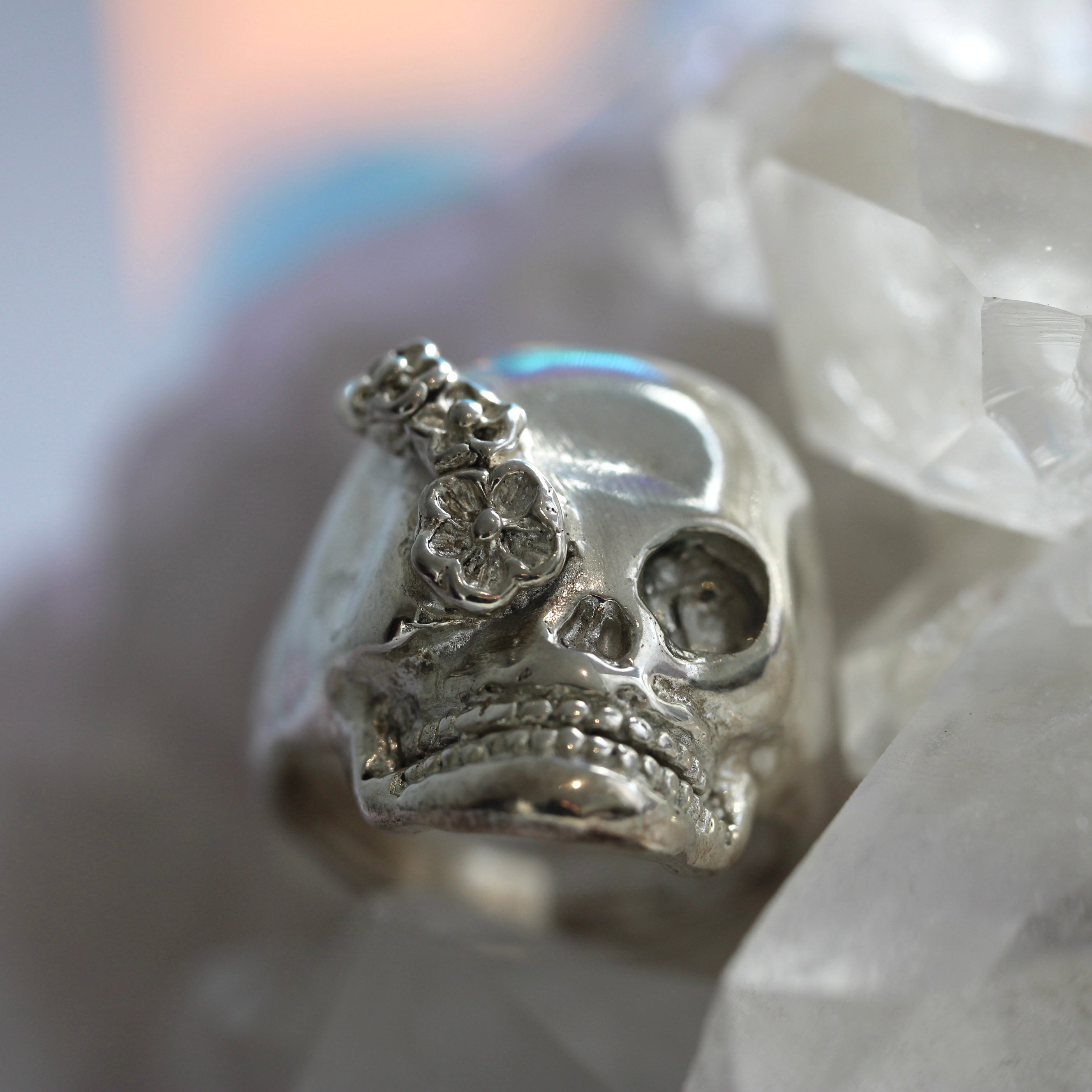 Silver skull ring with floral details on a white background