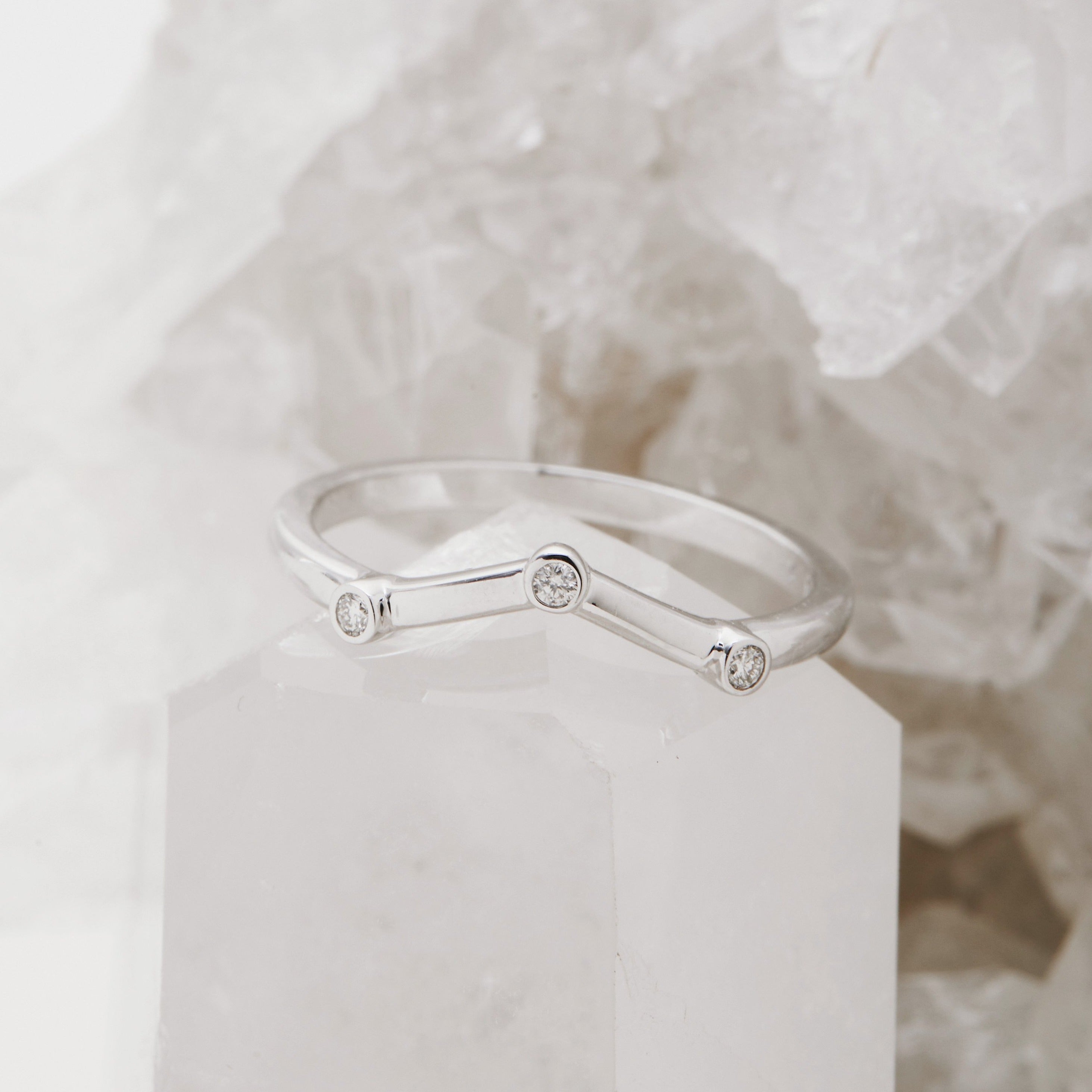 Chevron_shaped_wedding_band_with_flush_bezel_set_diamonds on a crystal