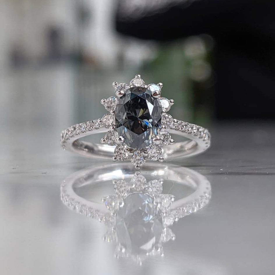 Oval floral halo diamond engagement ring in rose gold with sparkling cluster halo — classic bridal jewellery photographed on floral background.