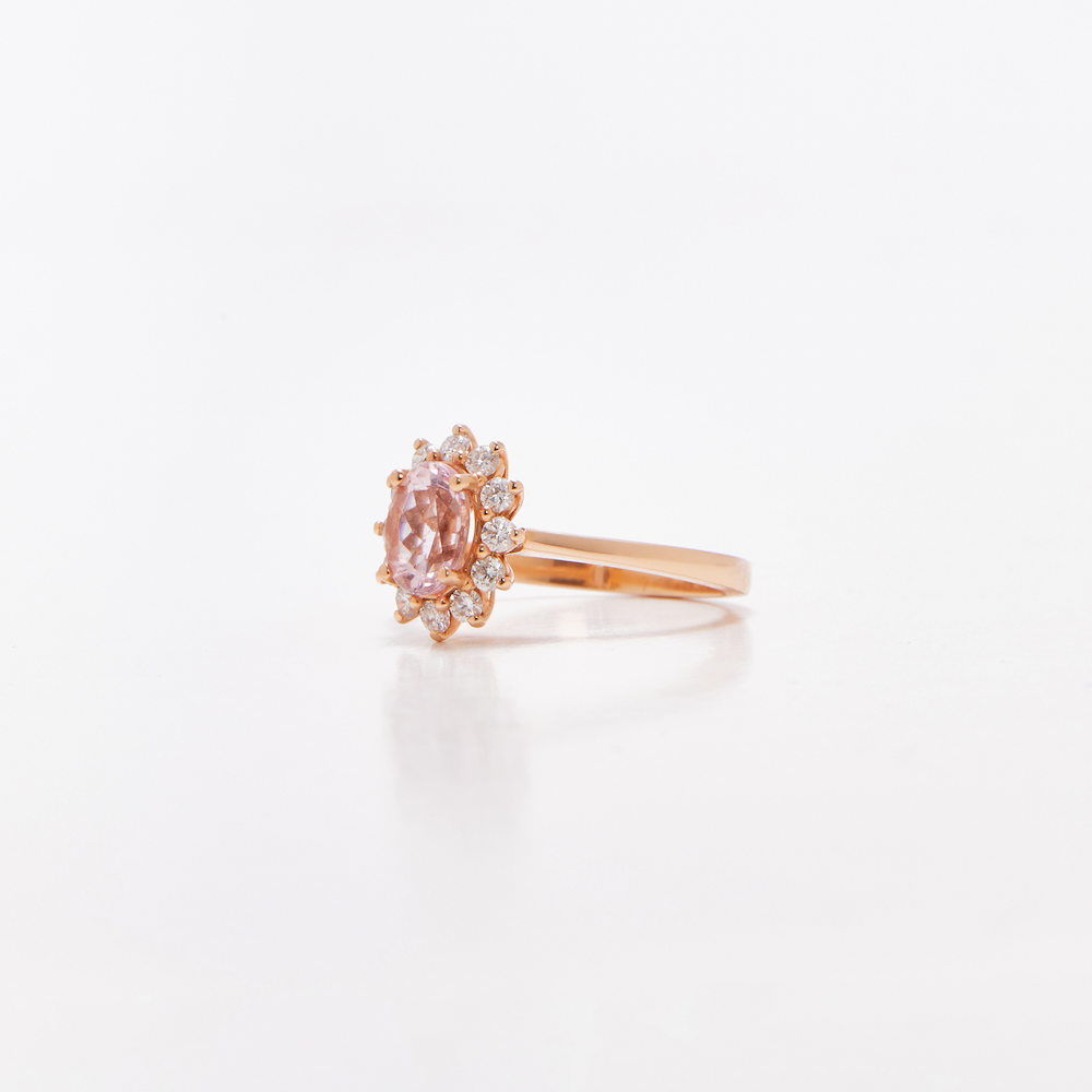 Oval floral halo diamond engagement ring in rose gold with sparkling cluster halo — classic bridal jewellery photographed on white background.