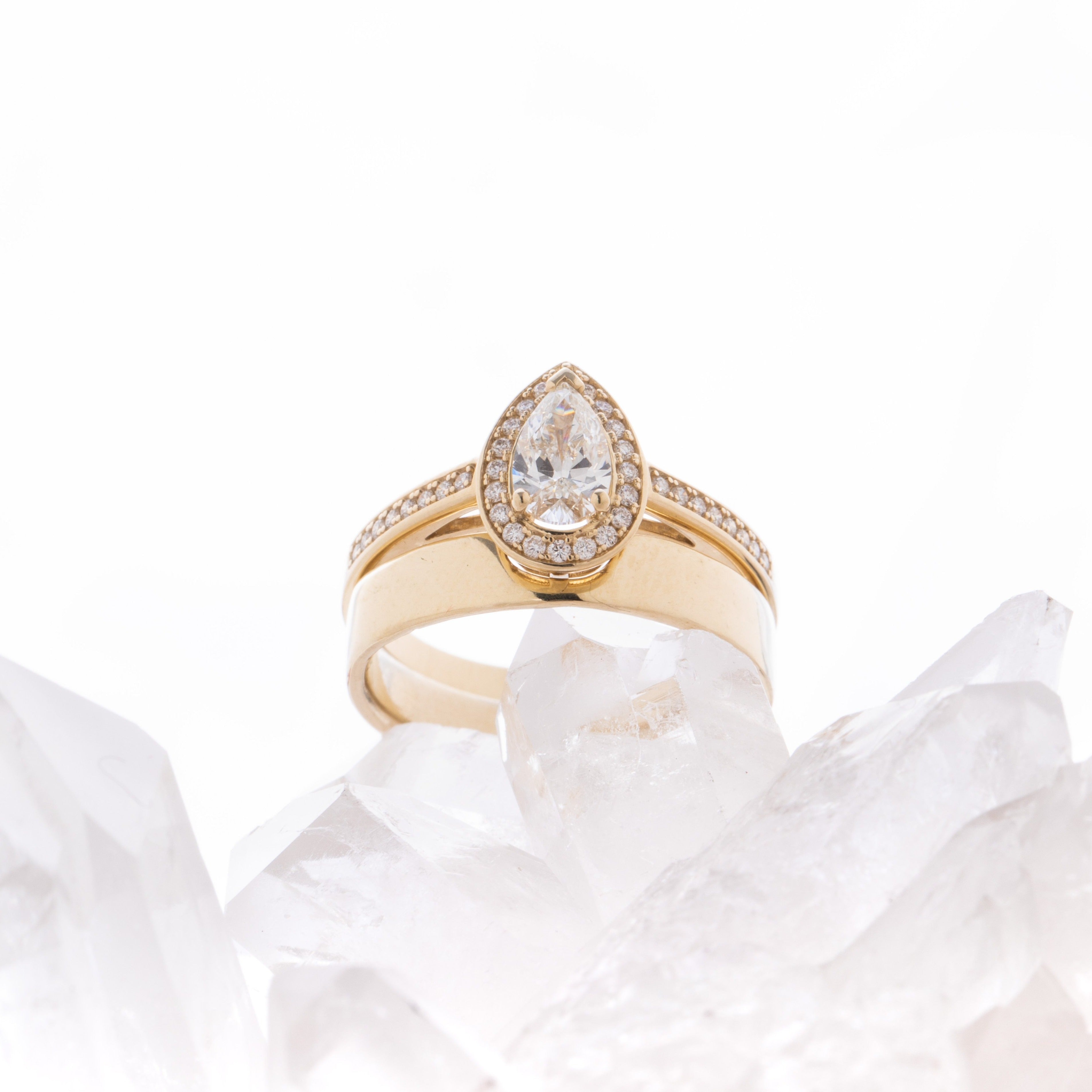 Rose gold halo diamond engagement ring with a thicker pavé band displayed on clean white crystal background — romantic bridal jewellery photo