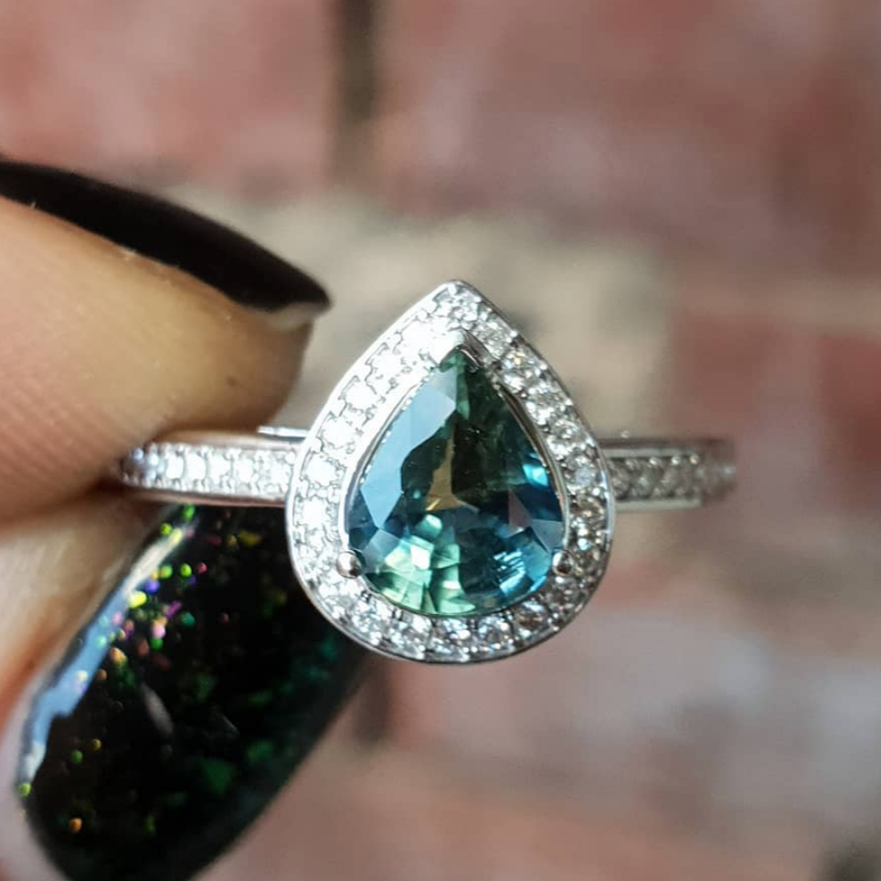 Pear halo sapphire engagement ring shown on hand — classic bridal set in white gold