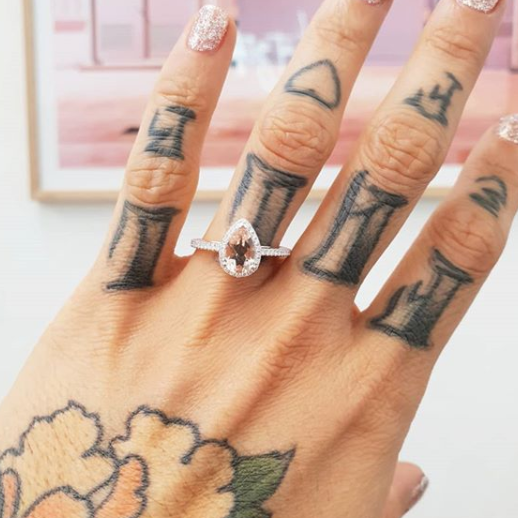 Pear halo diamond engagement ring paired with matching wedding band shown on hand — classic bridal set in white gold