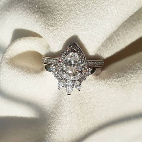 Pear halo diamond engagement ring paired with matching wedding band shown on white background — classic bridal set in white gold
