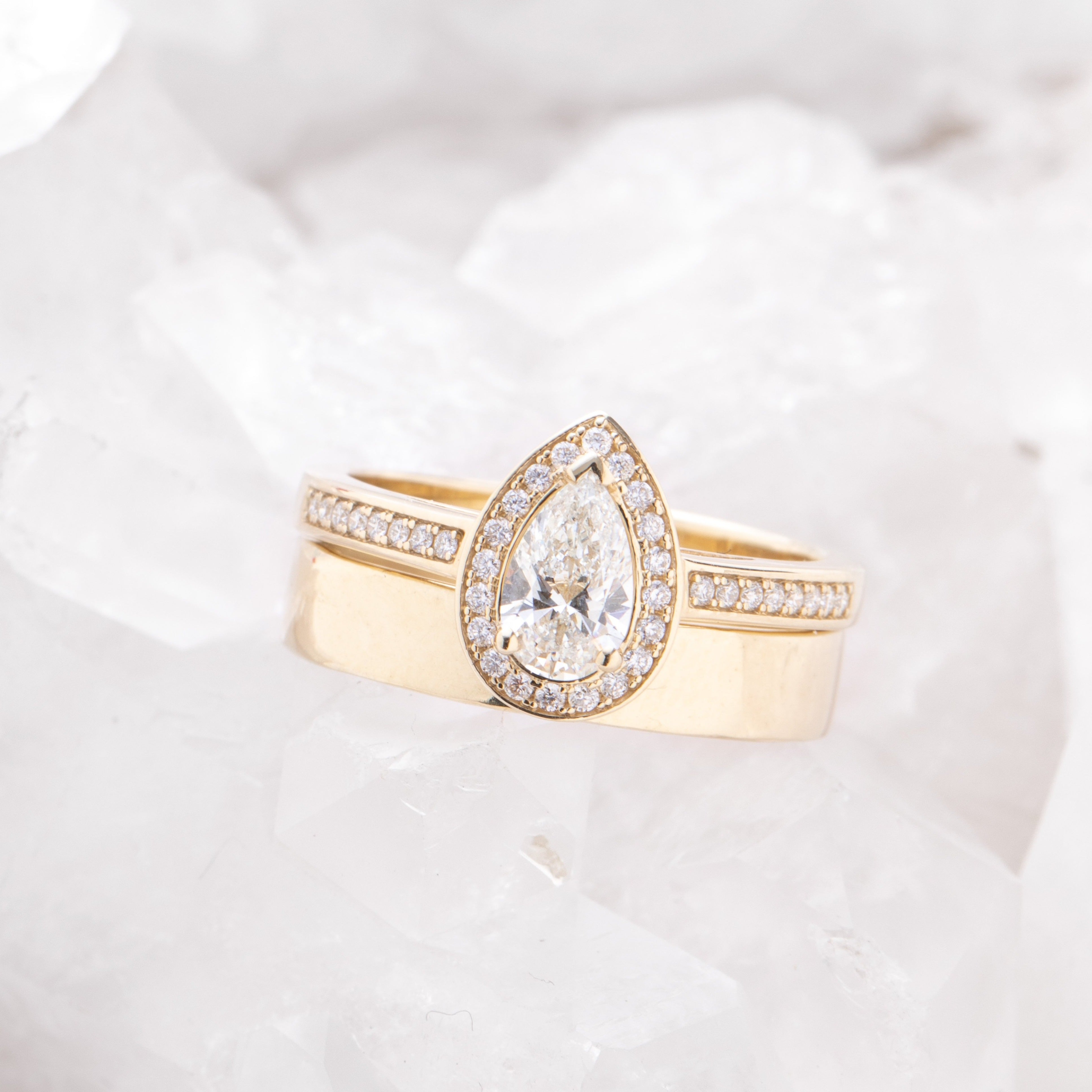 Rose gold halo diamond engagement ring with a thicker pavé band displayed on clean white crystal background — romantic bridal jewellery photo