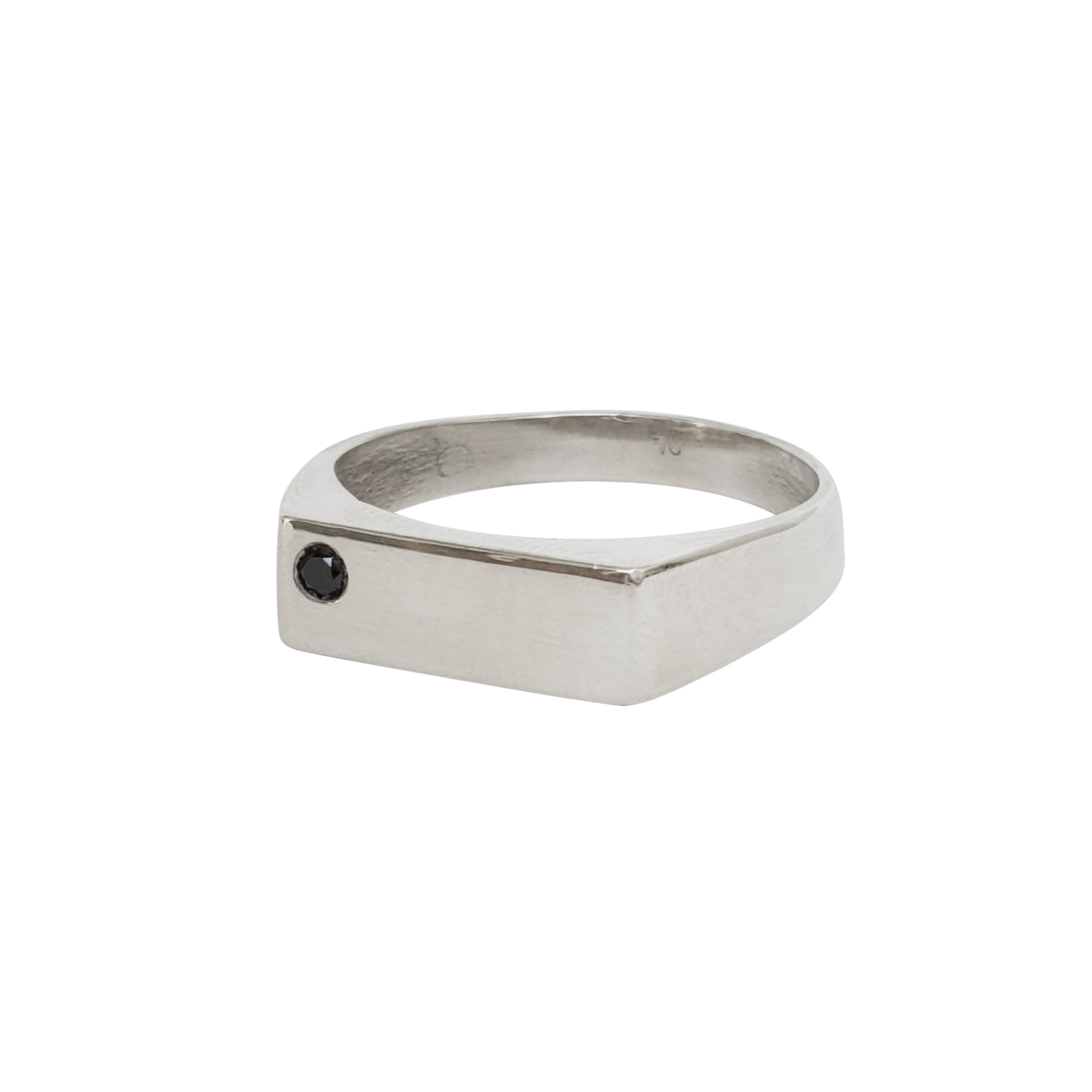 A silver-colored men's wedding band with a rectangular head featuring a single black diamond set on the left corner.