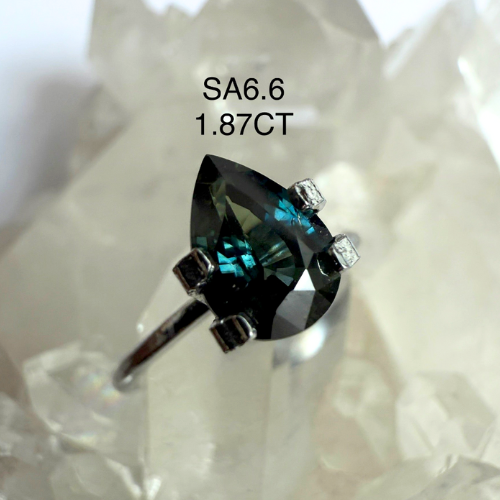 Ring with a large green gemstone and smaller diamonds on a white background