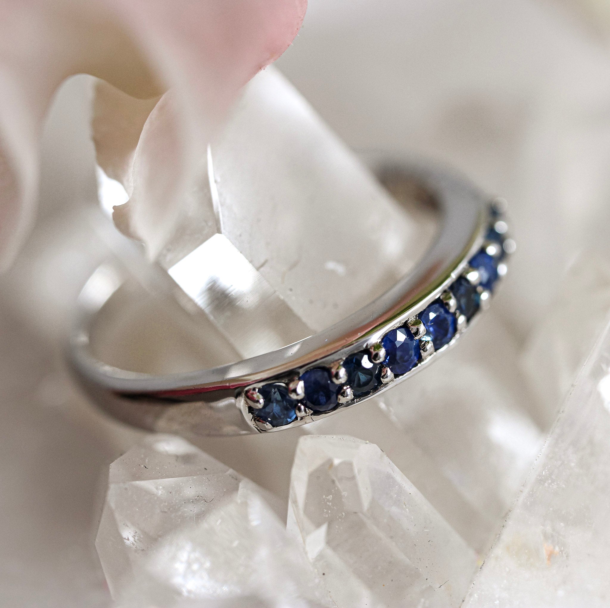 Silver ring with blue sapphire stones on a white stone surface
