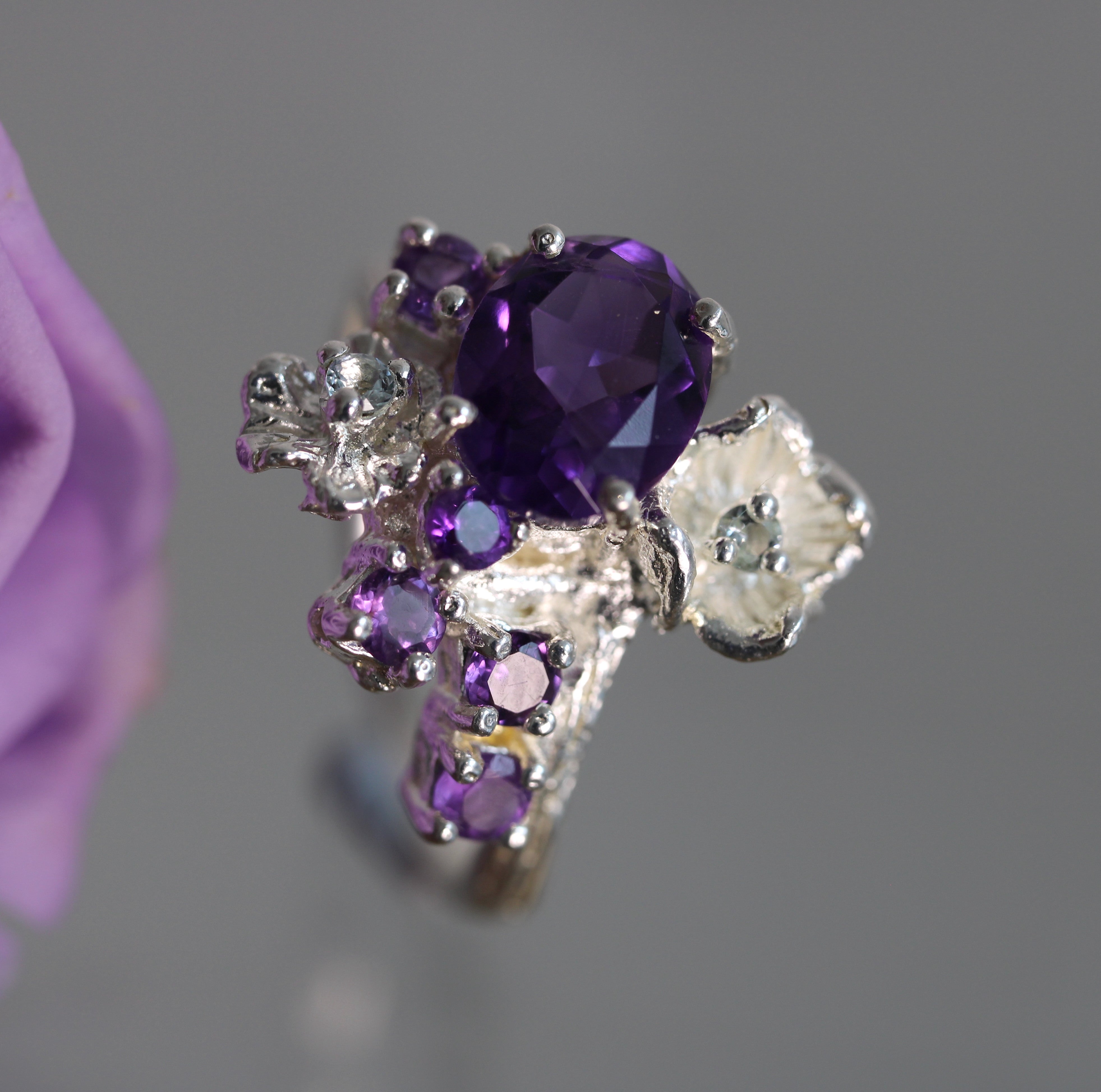 Silver ring with purple gemstones on a gray background