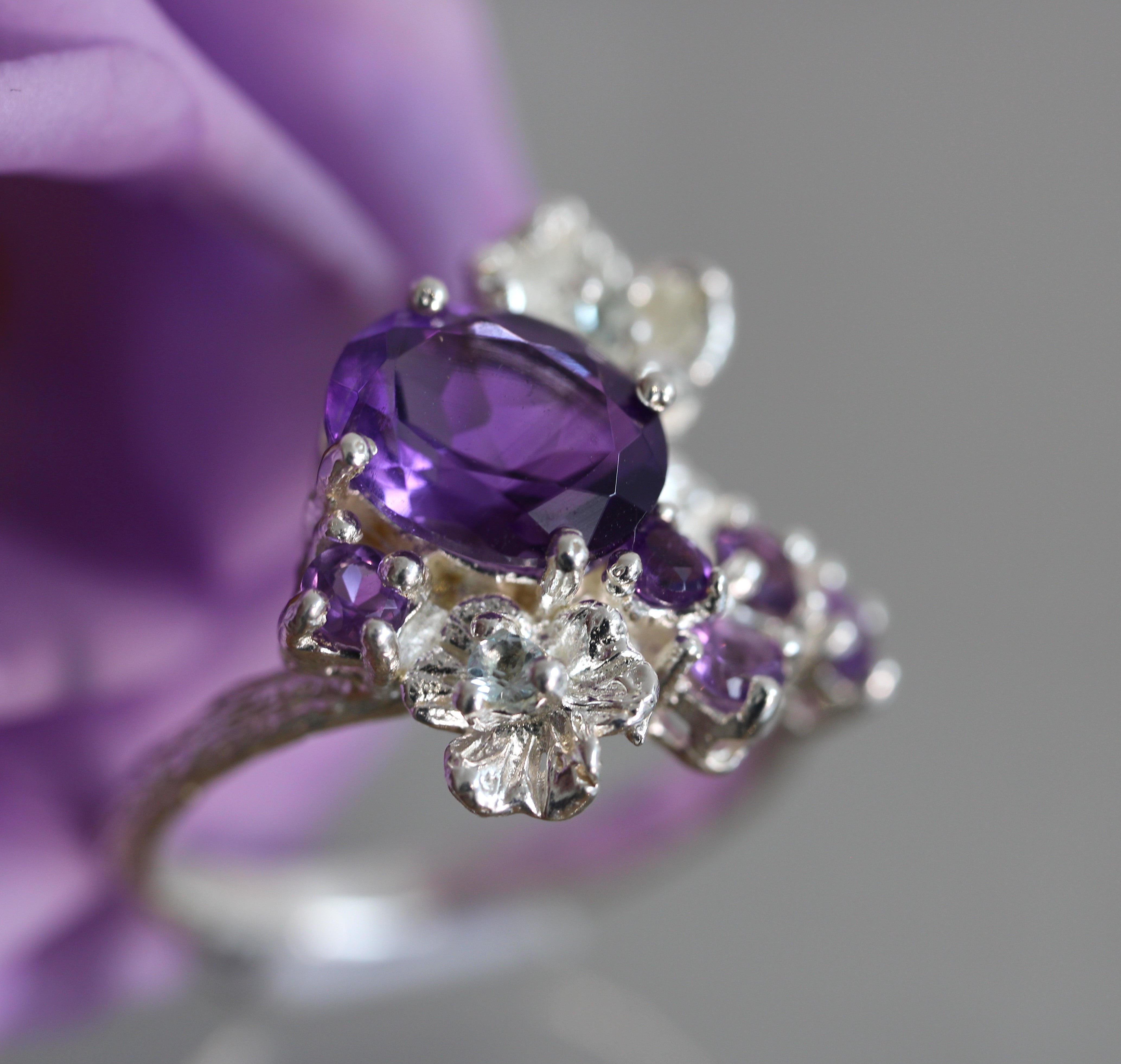 Silver ring with purple gemstones on a blurred purple background