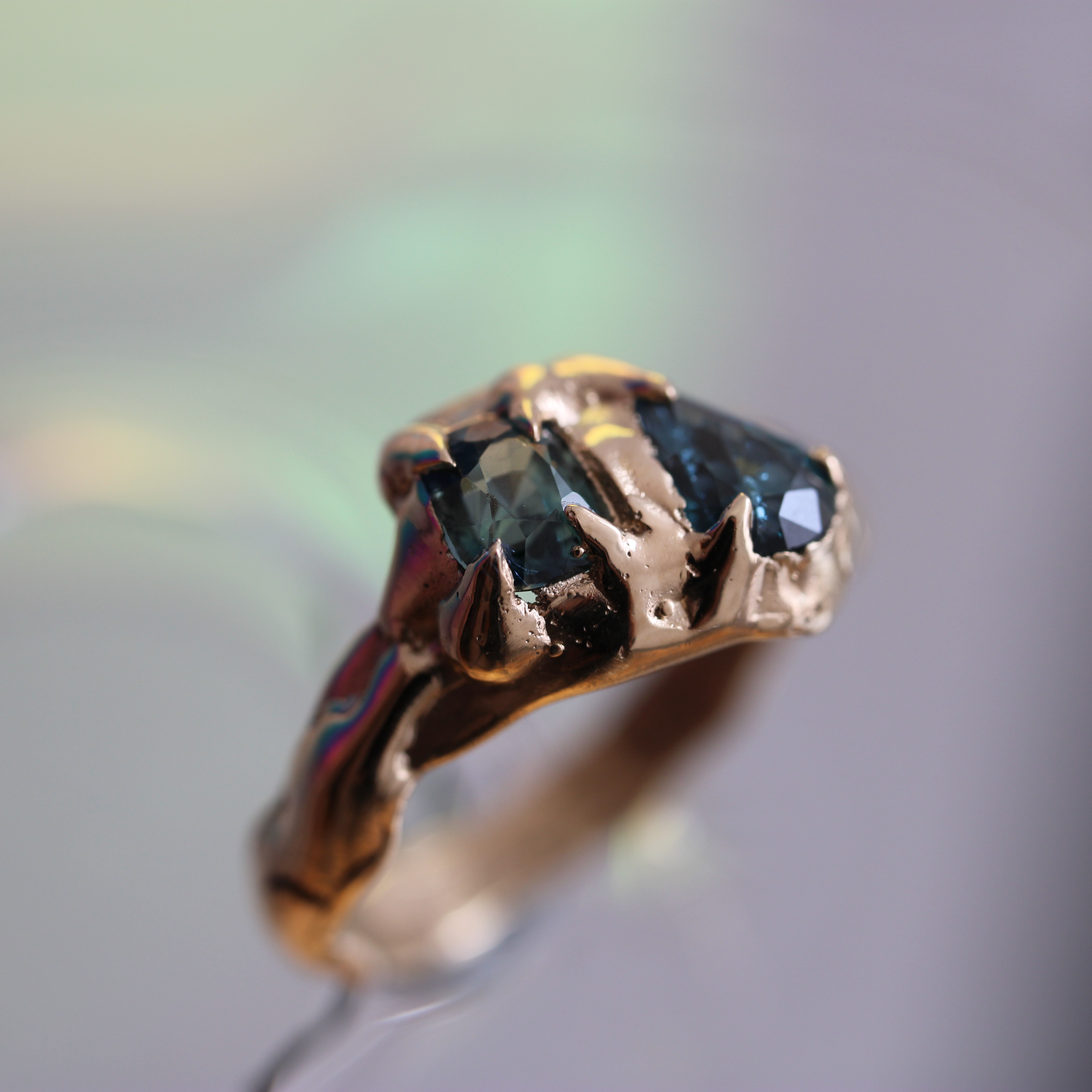 Gold ring with a green gemstone on a blurred background