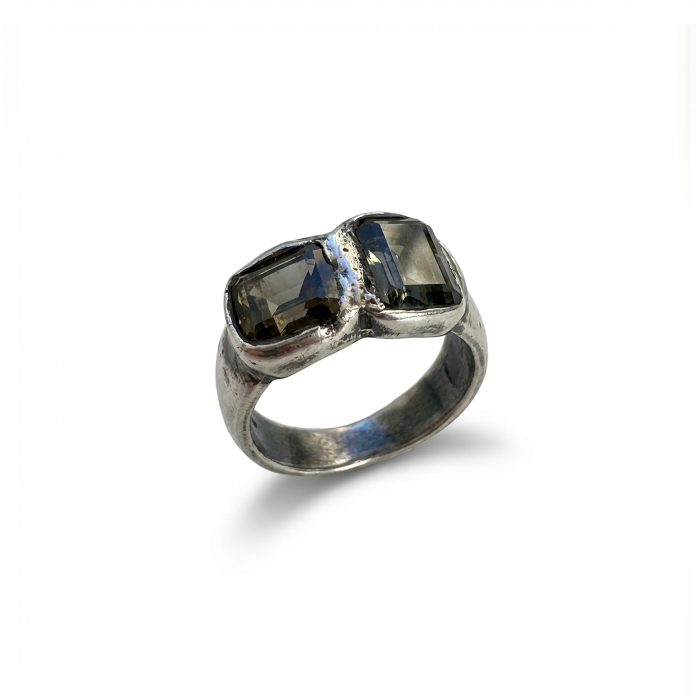 Silver ring with two dark gemstones on a white background