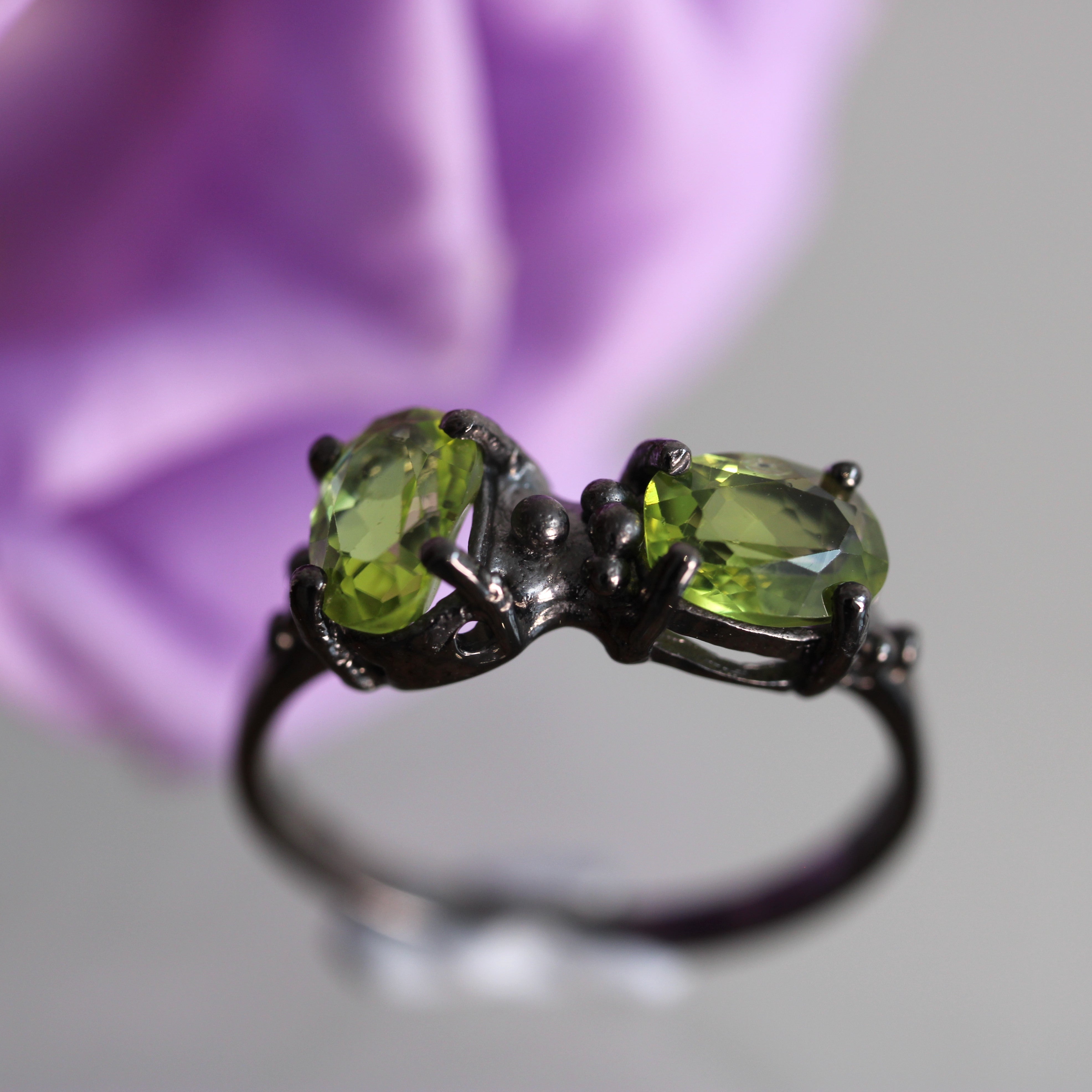 Ring with green gemstones on a blurred background
