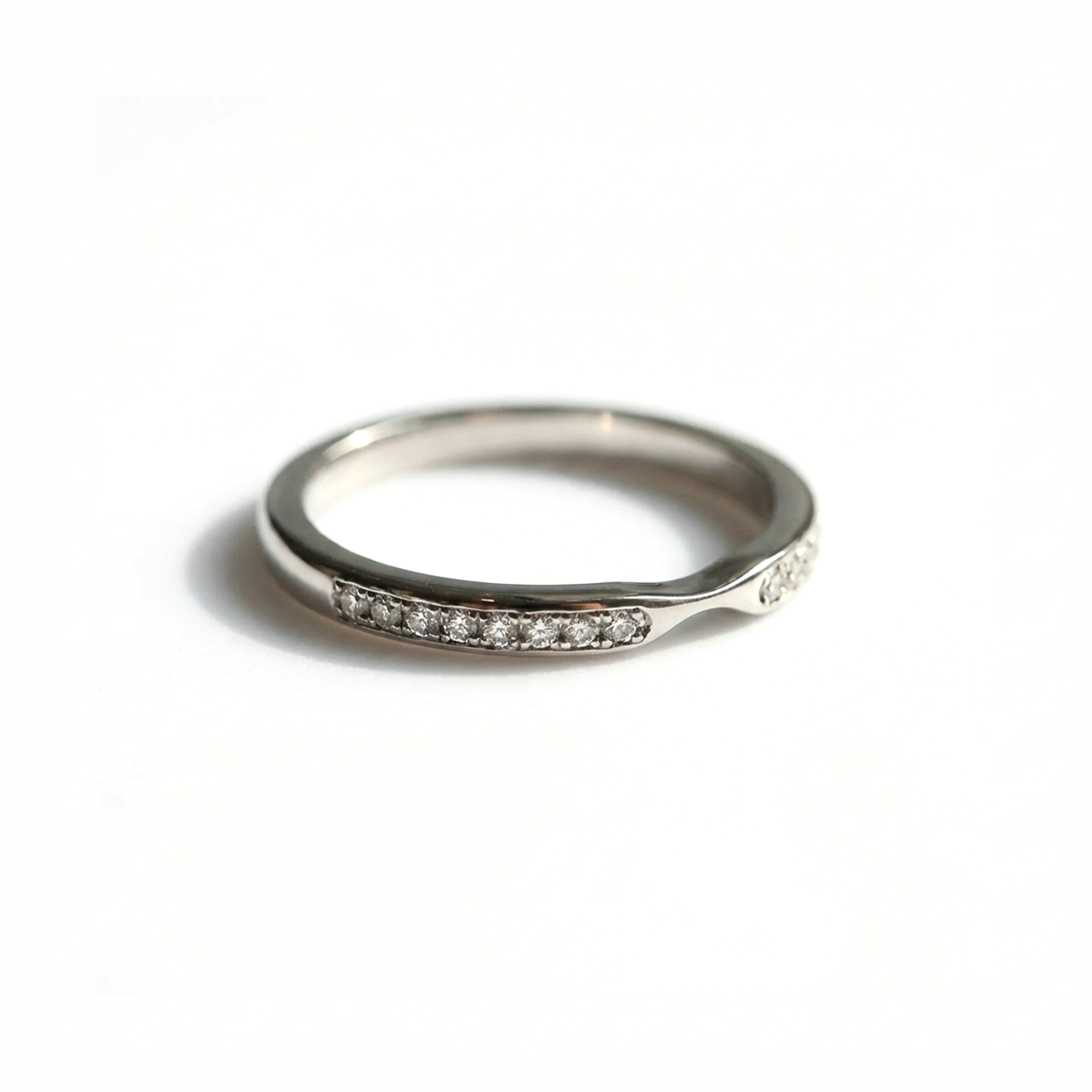 White gold wedding band ring with small diamonds on a white background